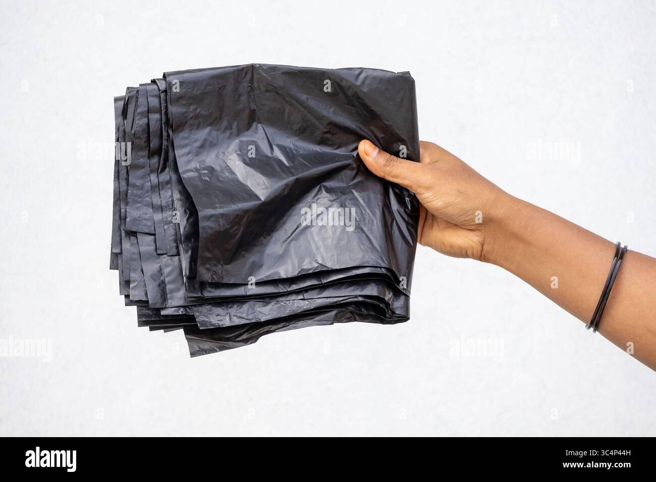 Primo piano di una mano femminile che espone sacchetti neri in polietilene per i contenitori dei rifiuti. Evidenziando i rifiuti comuni di plastica dannosi per l'ambiente e. Foto Stock