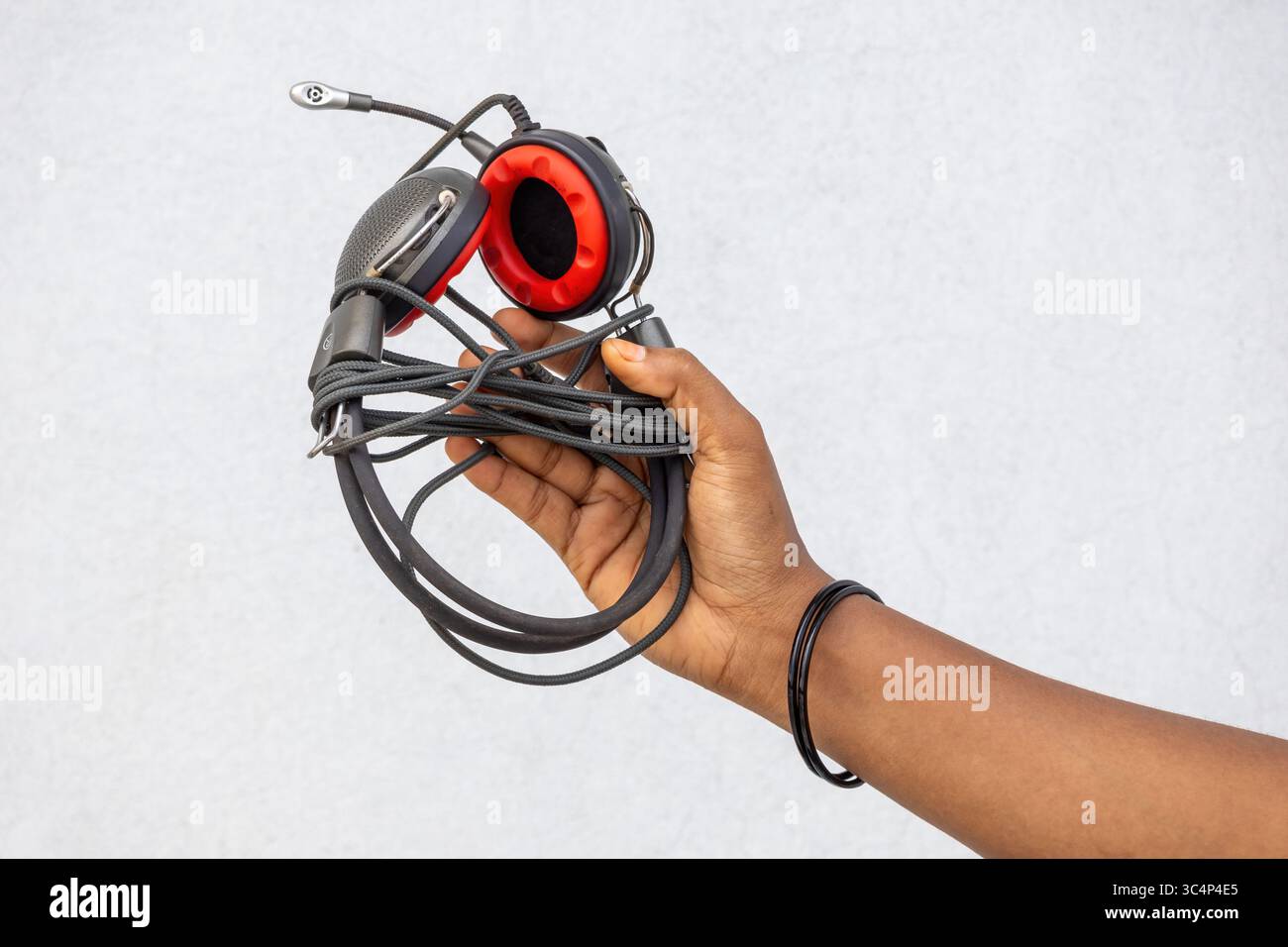 Primo piano di una mano femminile che tiene in mano cuffie vintage con cavo e microfono. Dispositivo audio retrò. Musica e tecnologia audio. Accesso all'ascolto classico Foto Stock