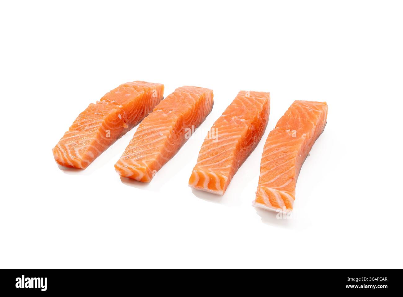 Quattro strisce di salmone crudo sono disposte diagonalmente su sfondo bianco. La loro consistenza e il loro colore si scontrano con l'ambiente pulito. Foto Stock