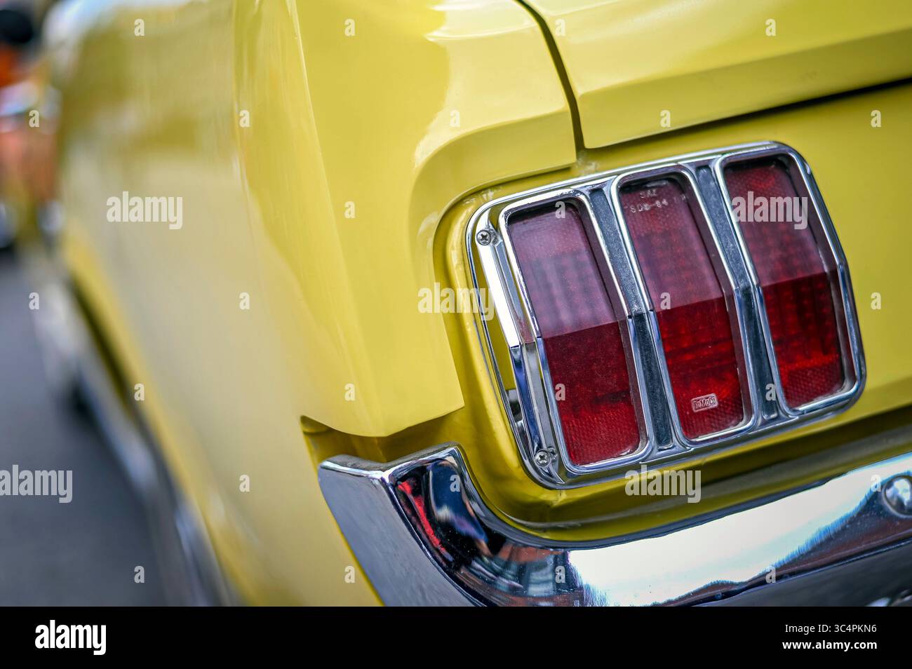 Primo piano di una luce di coda su una Ford Mustang gialla del 1965, fotografata durante un evento di auto d'epoca a Kitchener, Ontario, Canada. Luglio 2025. Foto Stock
