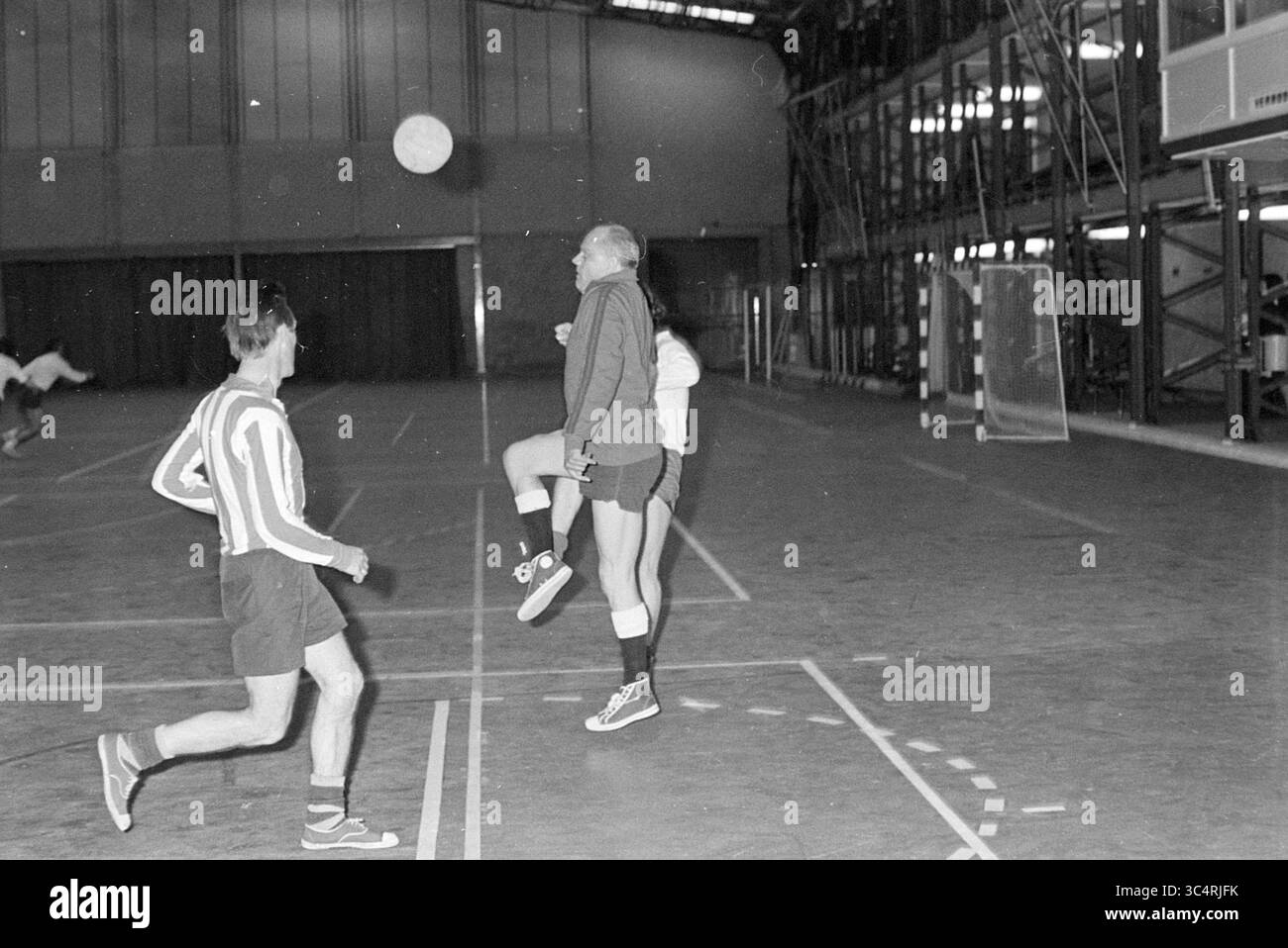 Stadio di calcio al coperto, calcio, 29-05-1972 Whizgle News, Dutch Desk, Paesi Bassi, 1950-2000 Un gruppo di atleti è impegnato in una partita di calcio al coperto, che mette in mostra movimenti dinamici, mentre un giocatore controlla con abilità la palla mentre altri scendono in attesa del gioco. L'ambientazione è caratterizzata da un'ampia struttura sportiva con linee marcate sul campo, che enfatizzano l'atmosfera competitiva. Foto Stock