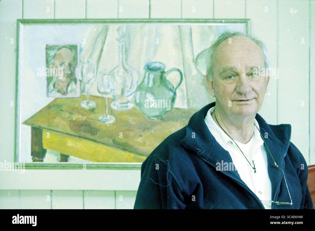 Wim van Gogh, Heemstede, Paesi Bassi, 03-04-2003 Whizgle News, Dutch Desk, i Paesi Bassi, 1950-2000 Un uomo si trova di fronte a una scena dipinta con un tavolo adornato di vetreria e una caraffa, accompagnato da un ritratto appeso al muro dietro di lui. L'ambiente trasuda un'atmosfera calda e artistica. Foto Stock