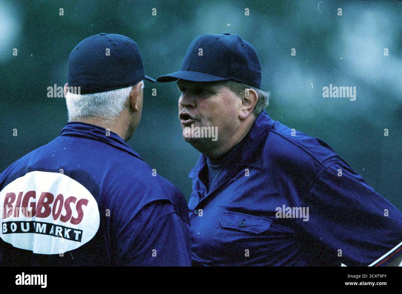 Baseball: Cuba - USA, 09-08-2000 Whizgle News, Dutch Desk, Paesi Bassi, 1950-2000 due persone con uniformi abbinate si impegnano in una conversazione tesa, con una che sembra esprimere frustrazione mentre l'altra ascolta intensamente. L'ambientazione suggerisce un momento emotivo, forse legato a una situazione competitiva. Foto Stock