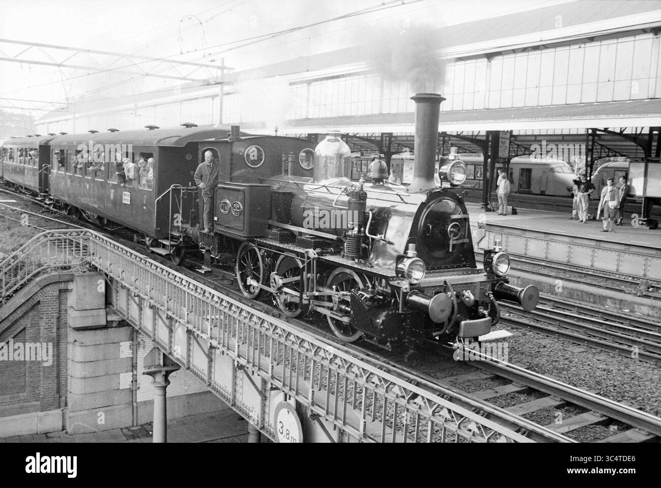 Treno a vapore bello alla stazione di Haarlem., treni, Haarlem, Nederland, 09-10-1987 Whizgle News, Dutch Desk, Paesi Bassi, 1950-2000 Una locomotiva a vapore d'epoca si ferma in una vivace stazione ferroviaria, emettendo fumo mentre i passeggeri attendono con ansia il loro viaggio. La scena cattura un senso di nostalgia, con carrozze tradizionali e viaggiatori vestiti in abiti d'epoca, circondati dai dettagli architettonici della stazione. Foto Stock