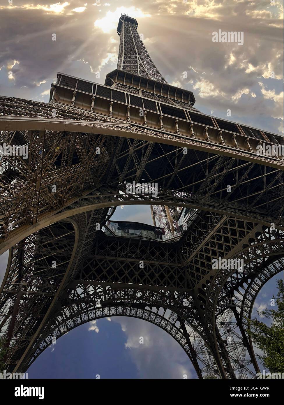 Vista sul fondo della Torre Eiffel, Parigi con i raggi del sole nel cielo coperto Foto Stock