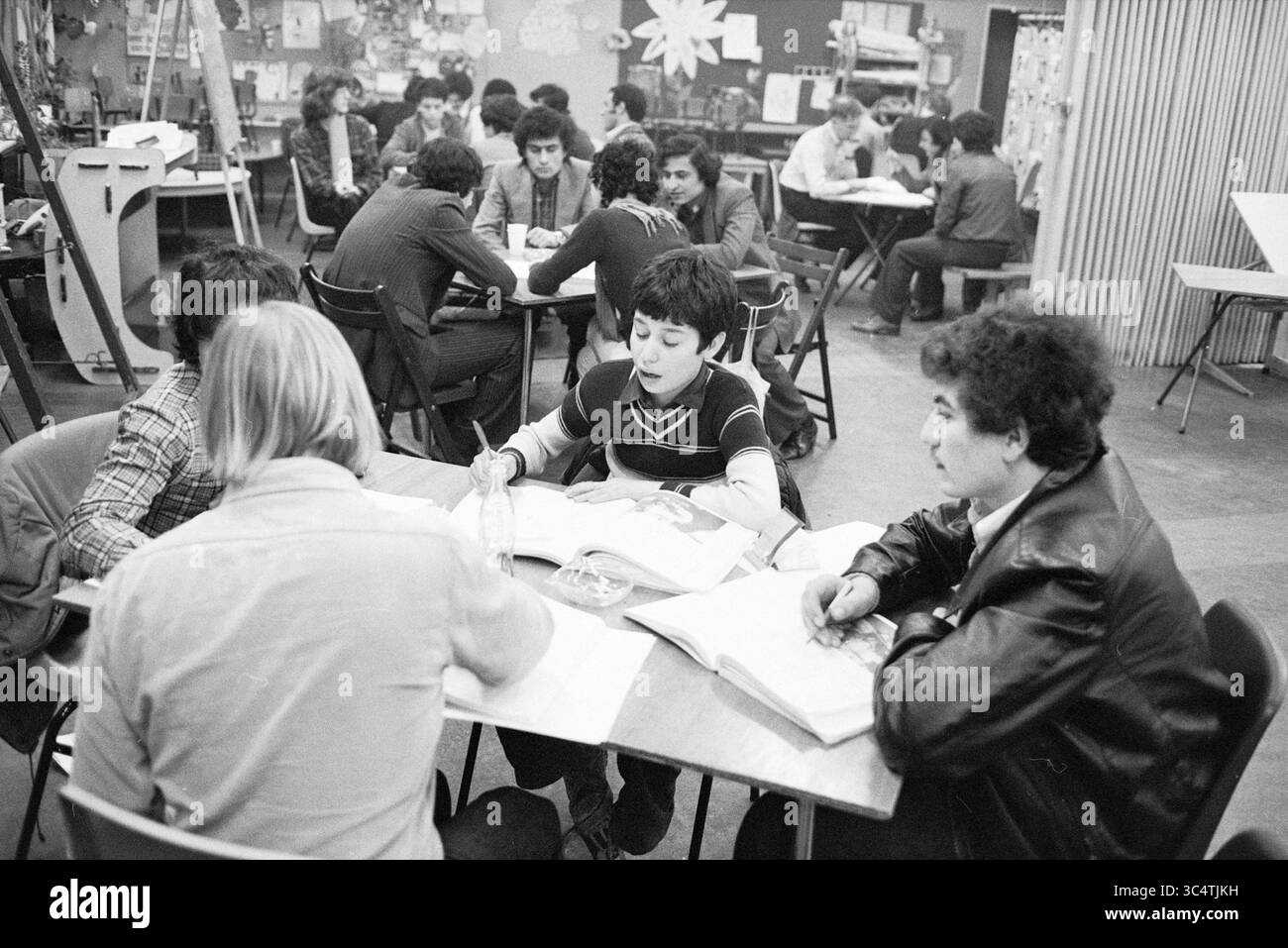 Lezioni di lingua olandese per turchi, stranieri, 16-03-1980 Whizgle News, Dutch Desk, Paesi Bassi, 1950-2000 Una vivace scena in classe con gruppi di studenti impegnati in discussioni e lavori di collaborazione, con libri, note e vari materiali scolastici sparsi tra i tavoli. L'atmosfera è focalizzata e dinamica, riflettendo un ambiente di apprendimento vivace. Foto Stock