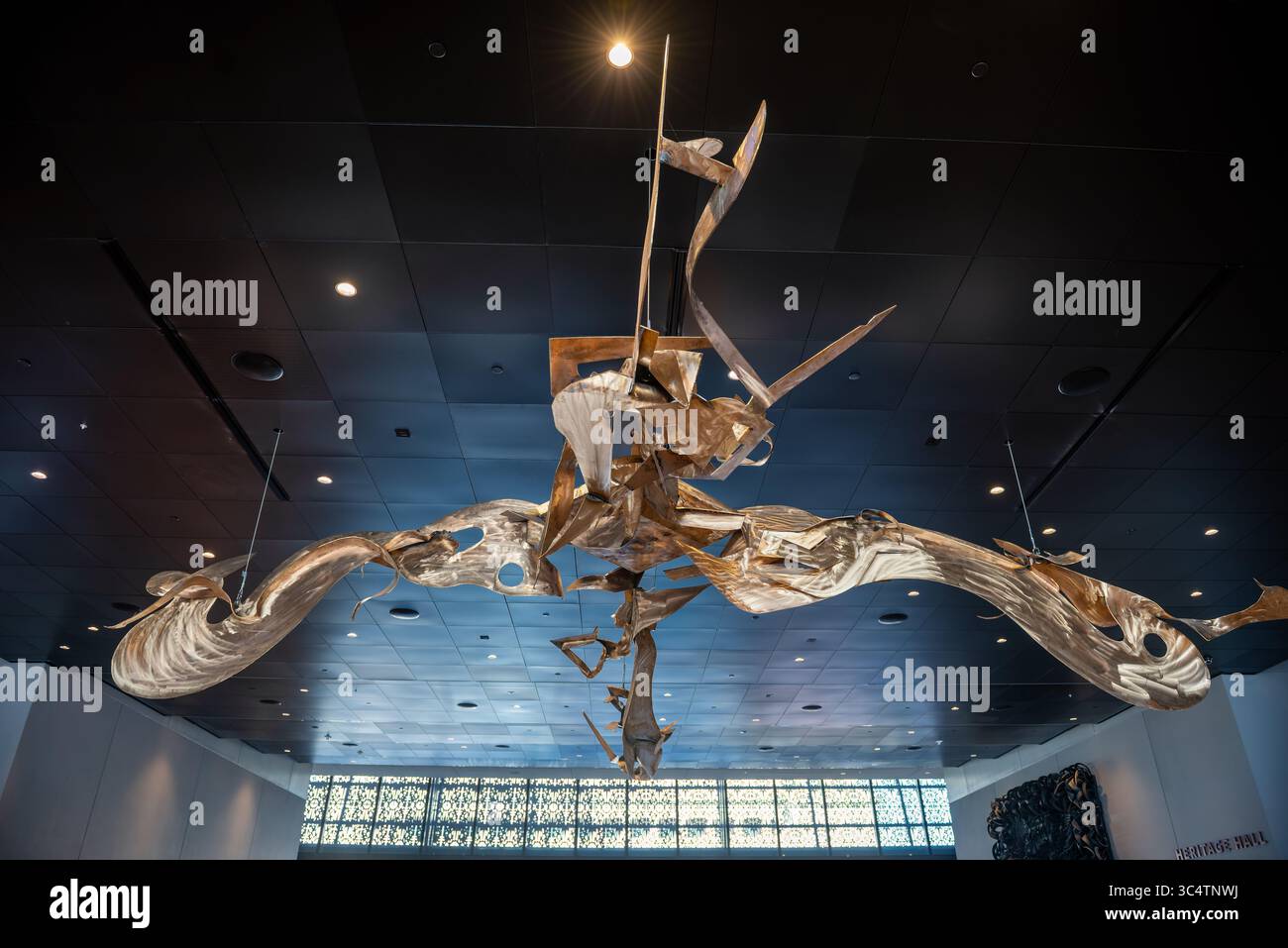 Scultura Swing Low all'interno del Museo di Storia Afroamericana | WASHINGTON — La scultura in bronzo e ottone saldato “Swing Low” di Richard Hunt è sospesa con cavi sopra la Heritage Hall, il foyer principale del Museo Nazionale della Storia e della Cultura Afroamericana. Il suo movimento a forma d'ala prende il titolo dal spiritual “Swing Low, Sweet Chariot”, una canzone a lungo associata alla Via Ferrata Clandestina e cantata dalle persone schiave come un'espressione codificata della speranza di liberazione. Foto Stock