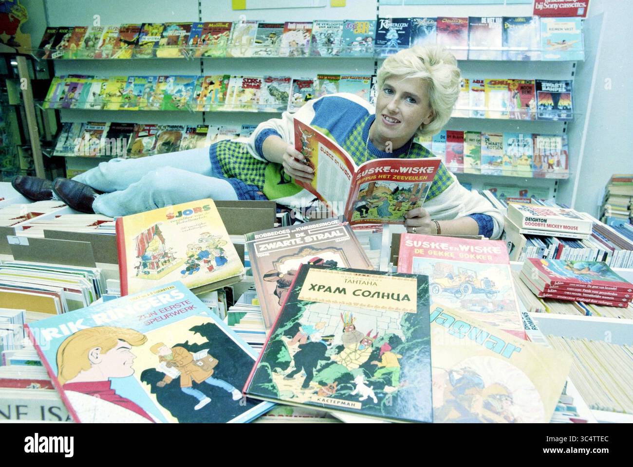 Negozio di fumetti, Klein Heiligland, 09-09-1996 Whizgle News, Dutch Desk, Paesi Bassi, 1950-2000 Una persona che si rilassa in mezzo a una variegata gamma di fumetti e graphic novel, leggendo con gioia uno mentre è circondata da una raccolta diversificata di titoli sovrapposti. L'atmosfera suggerisce un amore per la narrazione e l'avventura. Foto Stock