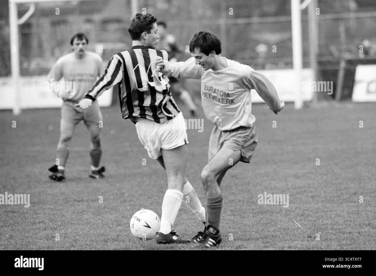 RCH - ODIN, Football R.C.H., 19-11-1988 Whizgle News, Dutch Desk, Paesi Bassi, 1950-2000 due giocatori sono impegnati in un momento competitivo sul campo di calcio, con un giocatore in una maglia a strisce che tenta di battere un rivale con una maglia tinta unita. L'atmosfera trasmette l'intensità del gioco mentre gareggiano per il controllo della palla, con altri giocatori visibili sullo sfondo. Foto Stock