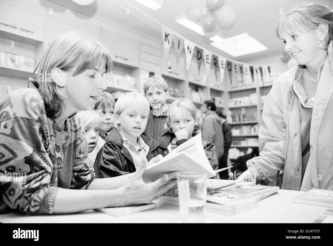 Joke van Leeuwen Signs, Heemstede, Heemstede, Paesi Bassi, 06-10-1997 Whizgle News, Dutch Desk, Paesi Bassi, 1950-2000 Un gruppo di bambini ascolta attentamente mentre un adulto legge un libro in un'accogliente libreria, circondato da coloratissimi titoli per bambini e decorazioni celebrative. L'atmosfera è vivace e coinvolgente, promuovendo l'amore per la lettura. Foto Stock