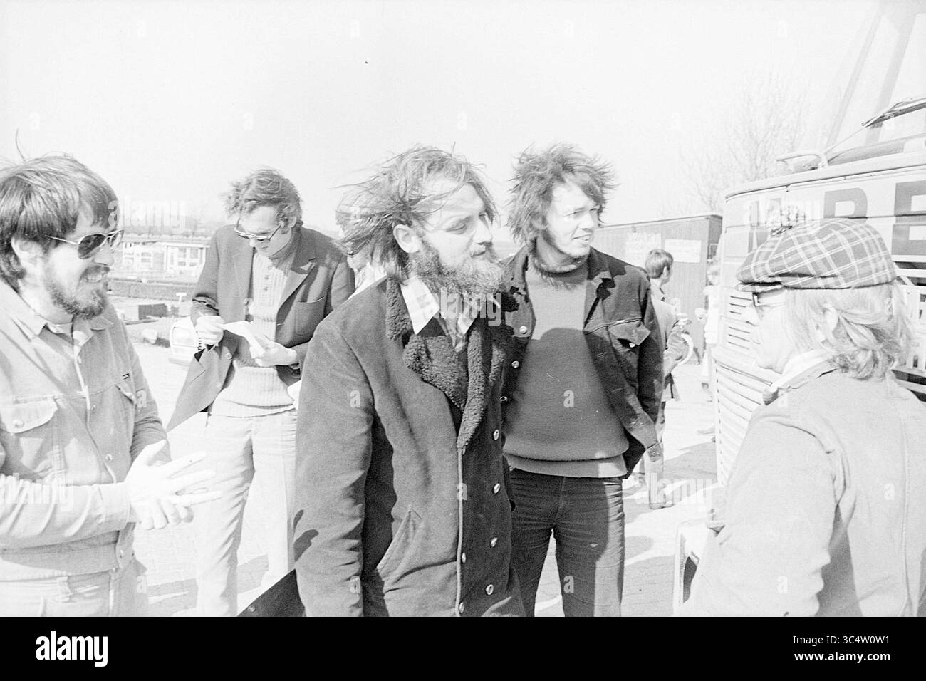 Protestation Garbage dump Beverwijk, dimostrazione, 22-04-1972 Whizgle News, Dutch Desk, Paesi Bassi, 1950-2000 Un gruppo di uomini si impegna in una conversazione animata all'aperto, con varie espressioni che riflettono cameratismo e curiosità. Alcune sono vestite con abiti casual, mentre altre presentano acconciature distinte, evidenziando un'atmosfera rilassata. Sullo sfondo, è possibile vedere un veicolo di grandi dimensioni, che suggerisce le attività in corso nelle vicinanze. Foto Stock