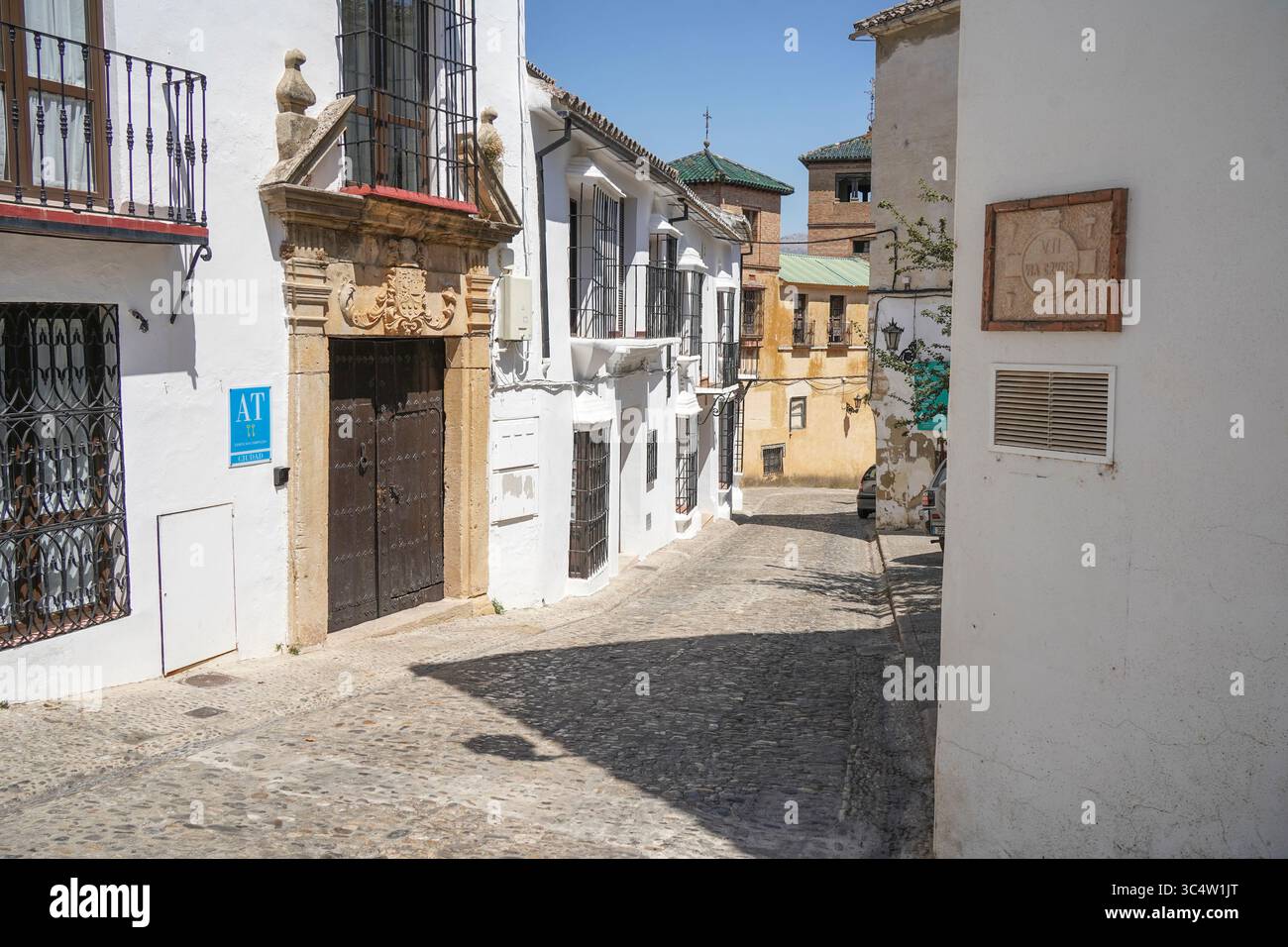 Vista sulla strada con ciottoli e case bianche spagnole nella città vecchia, nel centro storico di Ronda, Andalusia, Spagna. Foto Stock