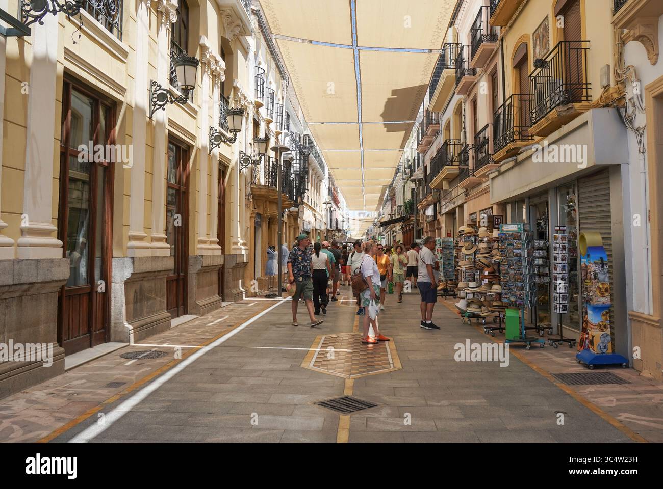 Tende al sole che coprono la strada principale dello shopping a Ronda in estate. Andalusia, Spagna. Foto Stock