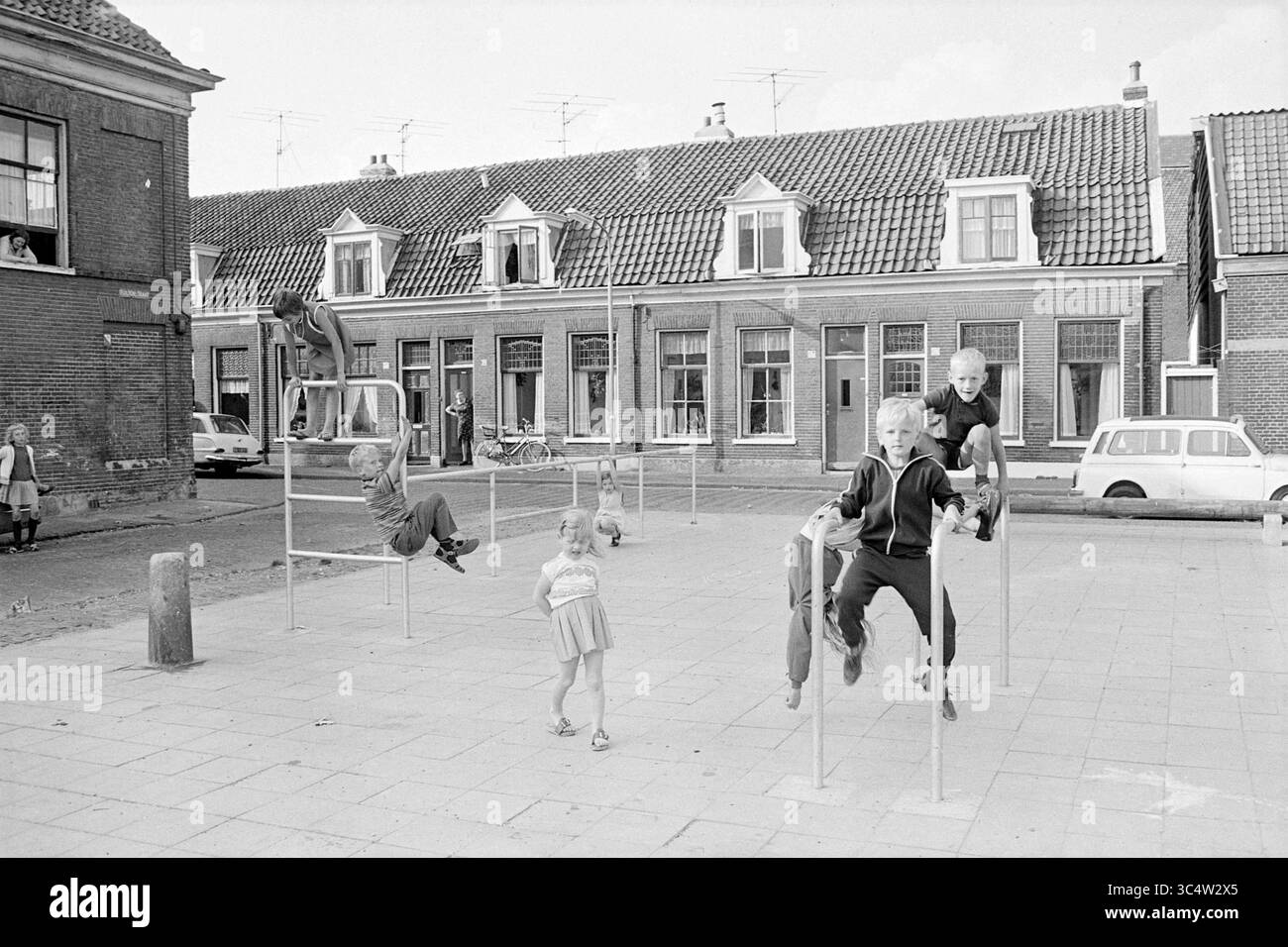 Angolo giochi per bambini Tulpenstraat, Van Marumstraat, Haarlem, Van Marumstraat, Paesi Bassi, 27-08-1968 Whizgle News, Dutch Desk, Paesi Bassi, 1950-2000 Una scena vivace cattura i bambini che giocano con le attrezzature all'aperto, mostrando la loro gioia ed energia. Nelle vicinanze ci sono alcuni adulti che guardano mentre si dedicano a varie attività. Case tradizionali con tetti piastrellati formano uno sfondo affascinante, che si aggiunge all'atmosfera nostalgica del parco giochi. Foto Stock
