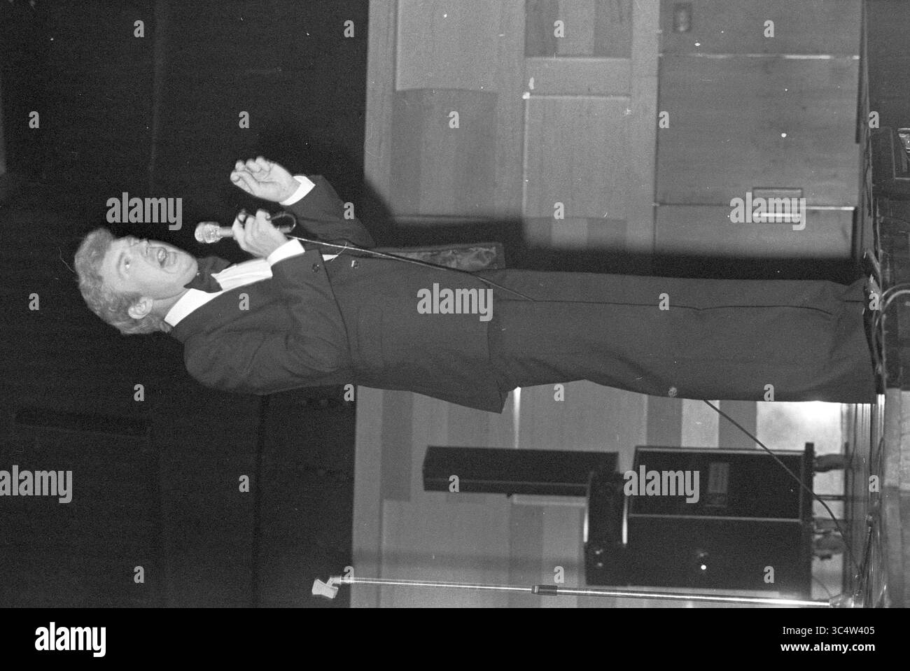 50th Anniversary of CBR, party staff, C.B.R., 08-10-1977 Whizgle News, Dutch Desk, i Paesi Bassi, 1950-2000 Un performer vestito con un smoking coinvolge appassionatamente il pubblico tenendo in mano un microfono, trasmettendo entusiasmo e carisma sul palco. Foto Stock