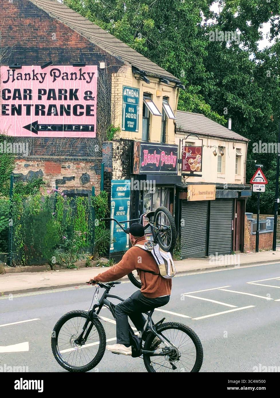 Uomo che pedala con un ciclo sulla spalla Foto Stock