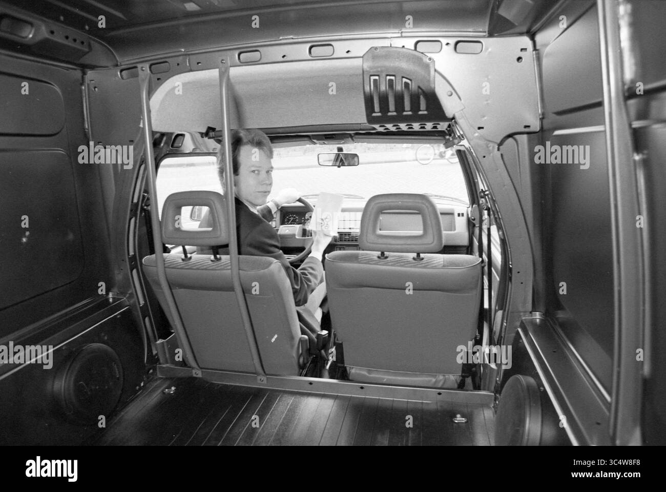 Pharma Business Zandvoort, 26-02-1993 Whizgle News, Dutch Desk, Paesi Bassi, 1950-2000 Un uomo siede sul sedile del conducente di un furgone, guardando indietro verso la fotocamera mentre tiene un documento. Gli interni sono minimalisti, con pareti in metallo e due sedili anteriori chiaramente visibili. Foto Stock