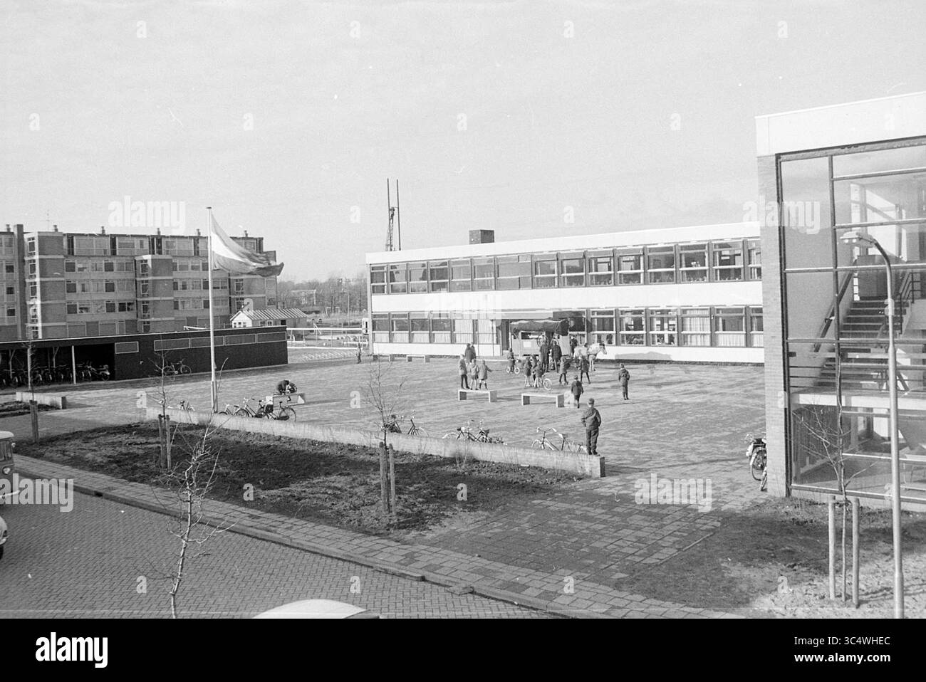 Responsabile della panoramica Huibersschool, Overviews, 16-02-1968 Whizgle News, Dutch Desk, Paesi Bassi, 1950-2000 Un vivace cortile scolastico pieno di studenti impegnati in varie attività, circondato da edifici moderni e biciclette parcheggiate nelle vicinanze. La scena cattura un'atmosfera vivace ed energica tipica di un giorno di scuola. Foto Stock