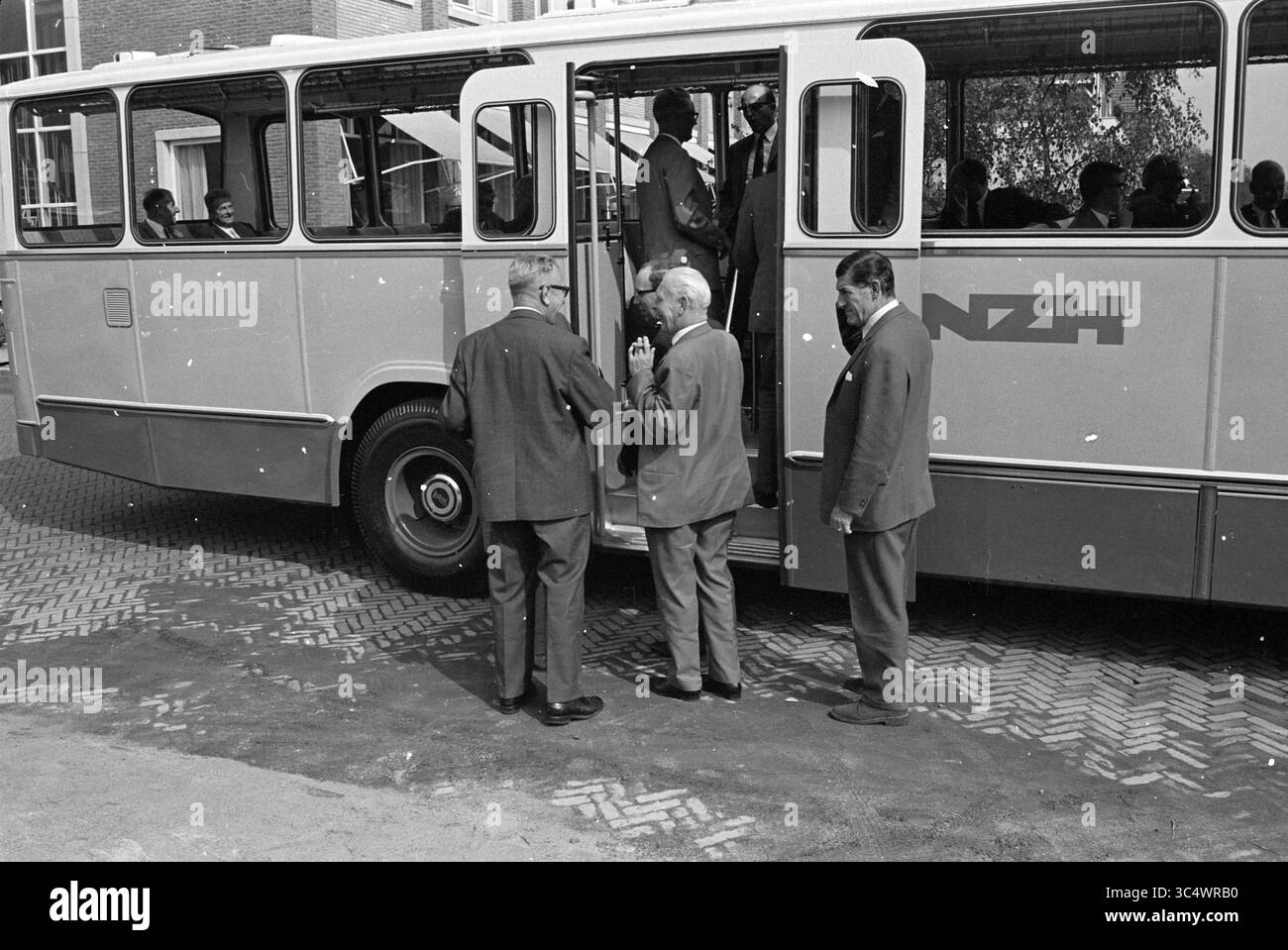 Trasferimento del nuovo autobus N.Z.H. a N.S., Noord Zuid Hollandse Vervoersmaatschappij N.V., nuova Zelanda, 25-08-1967 Whizgle News, Dutch Desk, Paesi Bassi, 1950-2000 Un gruppo di uomini in tuta si riunisce vicino a un autobus, osservando e interagendo tra loro mentre i passeggeri salgono a bordo. L'autobus presenta un logo chiaro ed è parcheggiato di fronte a un edificio, con le persone visibili all'interno. Foto Stock