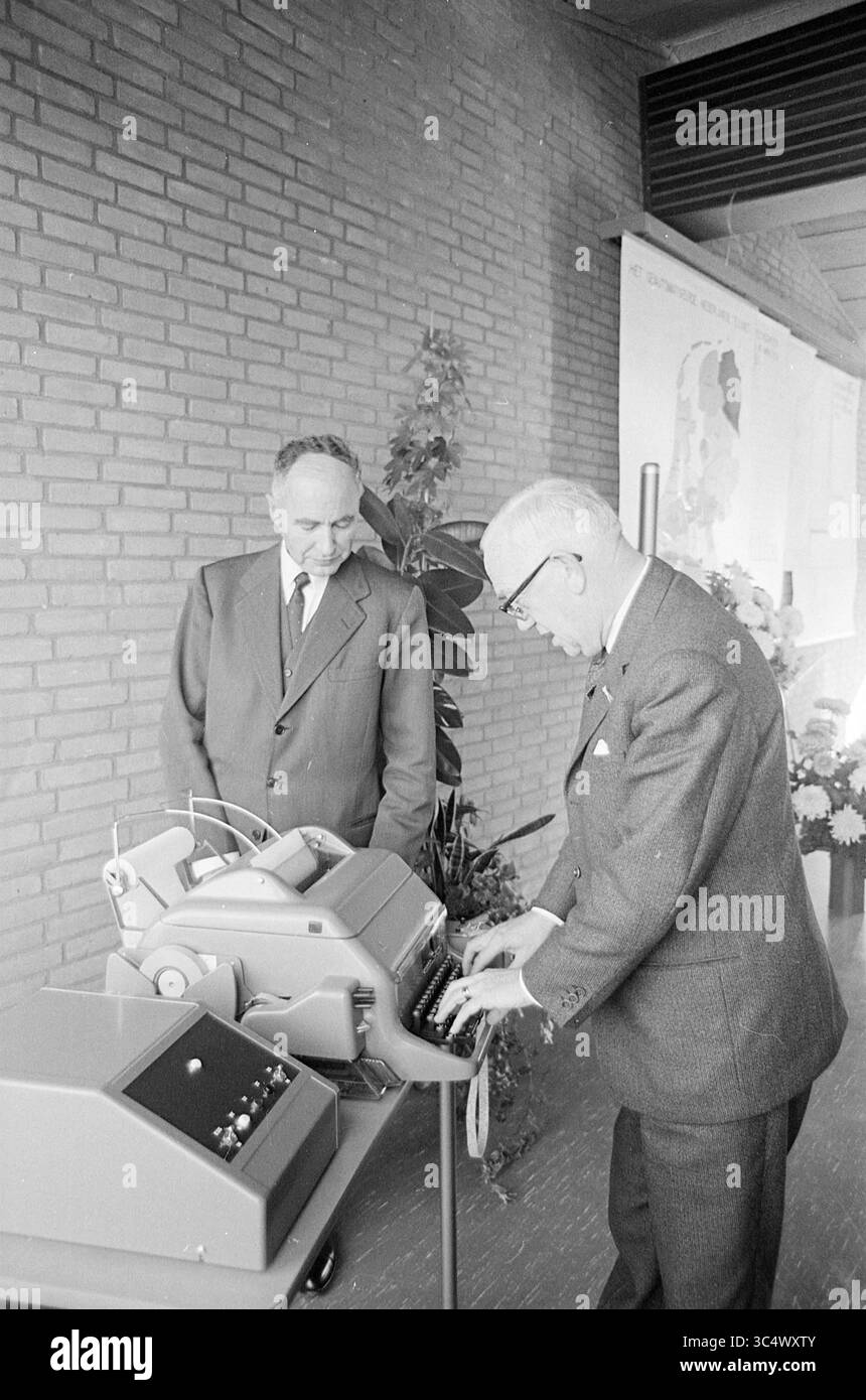 2 signori al telex, 00-10-1965 Whizgle News, Dutch Desk, Paesi Bassi, 1950-2000 due uomini si trovano vicino a un dispositivo di calcolo vintage in un ambiente moderno. Un individuo osserva attentamente mentre l'altro interagisce con la macchina, che è dotata di vari pulsanti e manopole. Lo sfondo include piante decorative e notevoli esposizioni a parete, che suggeriscono un'occasione formale o una dimostrazione. Foto Stock 2 signori al telex, 00-10-1965 Whizgle News, Dutch Desk, Paesi Bassi, 1950-2000 due uomini si trovano vicino a un dispositivo di calcolo vintage in un ambiente moderno. Un individuo osserva attentamente mentre l'altro interagisce con la macchina, che è dotata di vari pulsanti e manopole. Lo sfondo include piante decorative e notevoli esposizioni a parete, che suggeriscono un'occasione formale o una dimostrazione. Foto Stock
