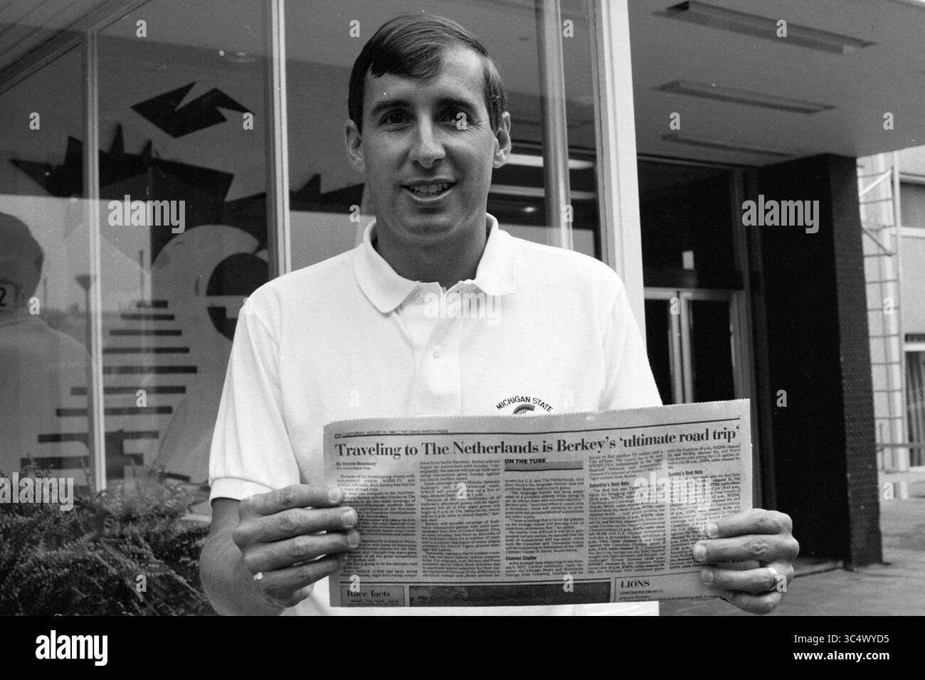 Rick Burkey reporter radiofonico americano, Baseball, radio, 19-08-1988 Whizgle News, Dutch Desk, i Paesi Bassi, 1950-2000 Un uomo con una polo sorride mentre regge un giornale con un articolo su un viaggio nei Paesi Bassi, con particolare attenzione al "miglior viaggio su strada" di Berkeley. Foto Stock