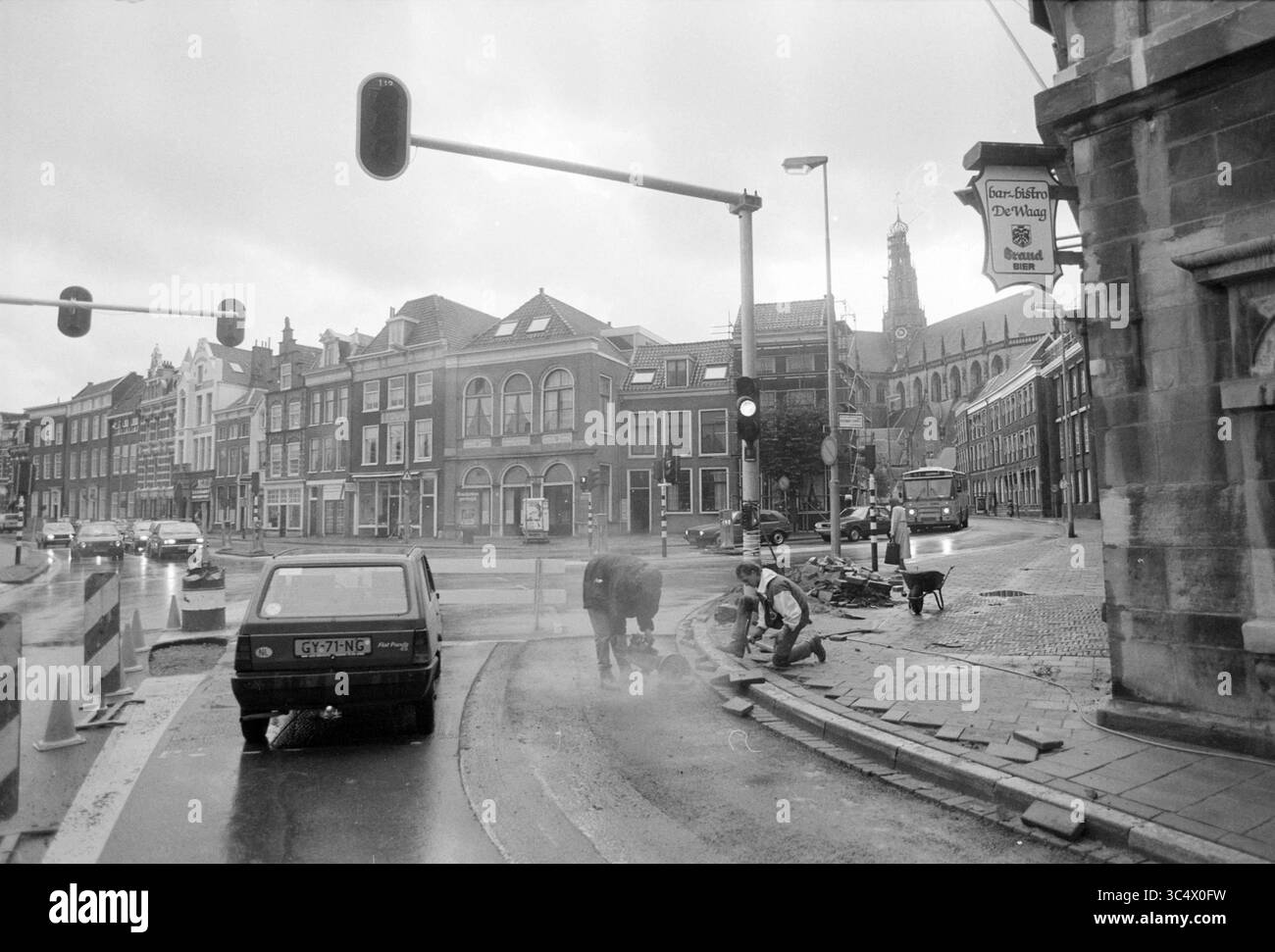 Scena del crimine, Santpoort, Santpoort, 06-09-1990 Whizgle News, Dutch Desk, i Paesi Bassi, 1950-2000 Una vivace scena urbana ospita i lavoratori delle costruzioni stradali impegnati nelle loro attività, mentre le auto attendono al semaforo. Gli edifici storici fiancheggiano la strada e sullo sfondo si erge una torre dell'orologio. I cieli nuvolosi aggiungono un senso di atmosfera all'ambiente vivace. Foto Stock