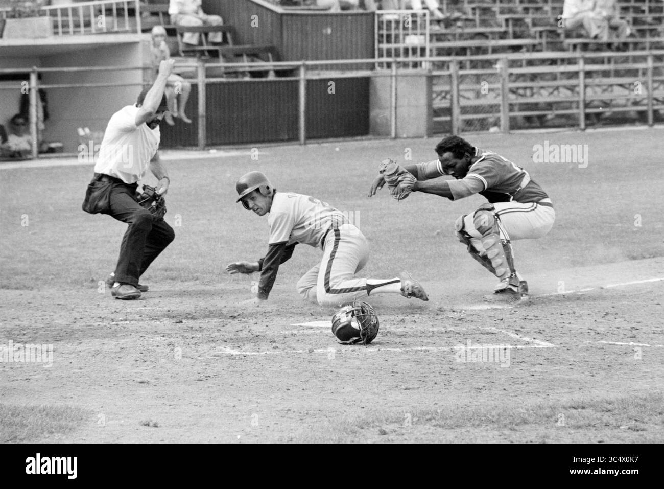 Baseball Nicols-Sparta, Baseball, 27-07-1979 Whizgle News, Dutch Desk, Paesi Bassi, 1950-2000 Un giocatore scivola nella piastra di casa, tentando di segnare mentre il ricevitore si prepara a tagliarlo fuori, mentre l'arbitro segnala il gioco. La scena cattura l'intensità di una partita di baseball, con gli spettatori sullo sfondo. Foto Stock