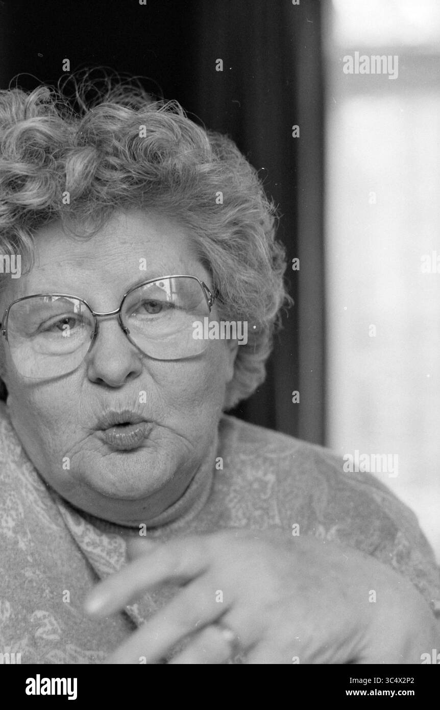 Sig.ra van Heyningen Haarlem North, Haarlem, Paesi Bassi, 27-09-1990 Whizgle News, Dutch Desk, i Paesi Bassi, 1950-2000 una donna anziana con capelli ricci e occhiali condivide una storia coinvolgente, la sua mano alzata in un gesto animato. Trasuda calore e personalità, invitando coloro che le circondano nel suo mondo. Foto Stock