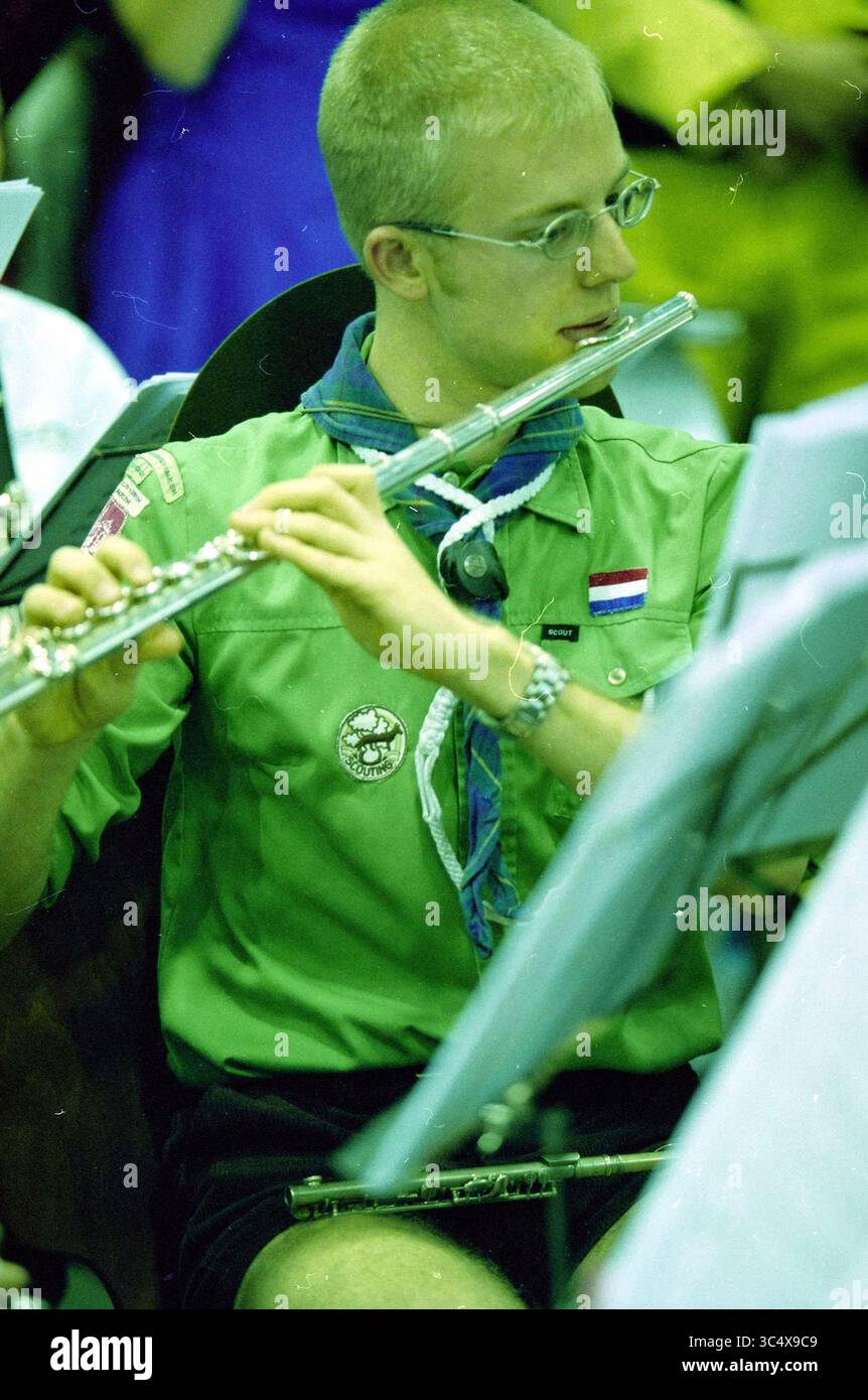 Roald Dahl, prove Paswerk, Cruquius, Cruquius, 22-03-2003 Whizgle News, Dutch Desk, Paesi Bassi, 1950-2000 Un giovane musicista in uniforme da ricognitore verde suona il flauto, concentrandosi sulla loro esibizione in mezzo a un raduno di altri membri della band, con fogli musicali davanti a loro. La scena cattura un momento di dedizione e di lavoro di squadra in un ambiente musicale. Foto Stock