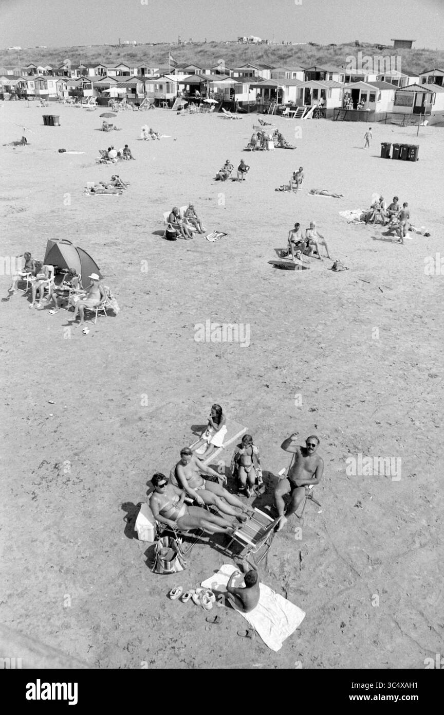 Toccare al di sopra di KL. Beach, IJmuiden, IJmuiden, Paesi Bassi, 02-08-1994 Whizgle News, Dutch Desk, Paesi Bassi, 1950-2000 Una vivace spiaggia piena di bagnanti che si rilassano sulla sabbia, godendosi il sole estivo. Nelle vicinanze, una fila di capanne sulla spiaggia fornisce rifugio, mentre altri si impegnano in conversazione e relax. Foto Stock