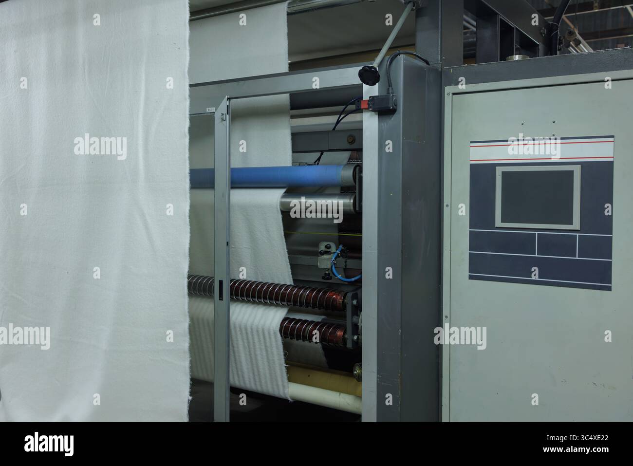 La macchina tessile automatizzata elabora il tessuto in una fabbrica moderna, mostrando una produzione avanzata ed efficienza Foto Stock