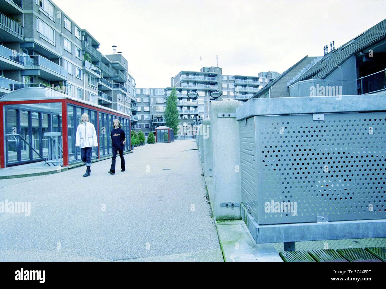 Engelenburg, Haarlem, Engelenburg, Paesi Bassi, 21-09-2001 Whizgle News, Dutch Desk, Paesi Bassi, 1950-2000 due persone passeggiano piacevolmente lungo un moderno vialetto urbano fiancheggiato da edifici contemporanei. La scena presenta un mix di strutture residenziali ed elementi decorativi, creando una miscela di architettura e spazio aperto. Foto Stock