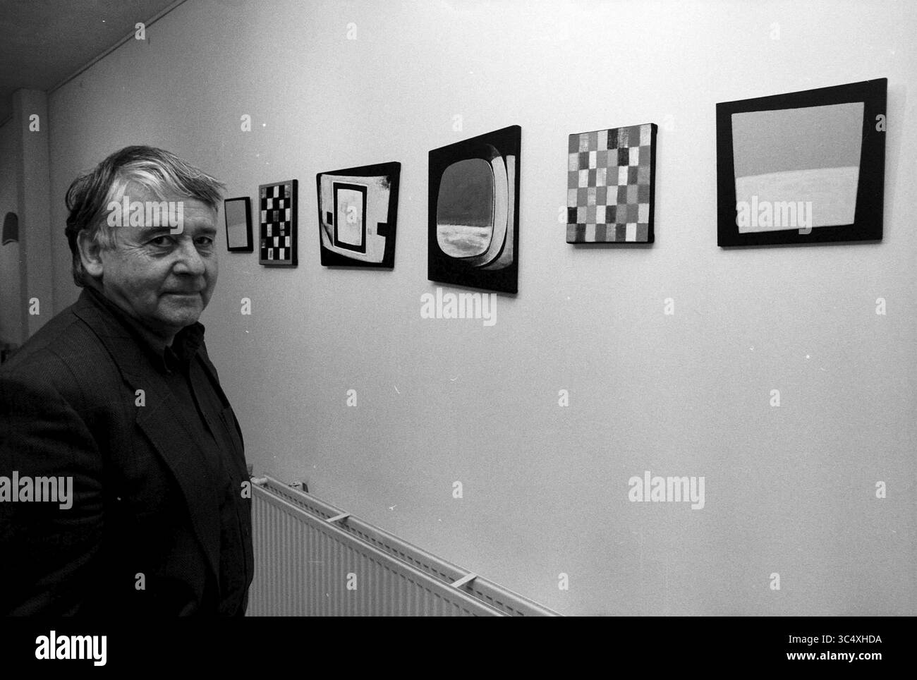 Jack Verweij in Rumpff Gallery, Haarlem, Spaarnwouderstraat, Paesi Bassi, 19-01-1997 Whizgle News, Dutch Desk, Paesi Bassi, 1950-2000 Un uomo si trova accanto a una serie di opere d'arte astratte esposte sul muro di una galleria, che mostrano una varietà di forme e motivi. Osserva attentamente i pezzi, che includono disegni geometrici e colori contrastanti. L'ambiente suggerisce una mostra d'arte, che mette in evidenza l'intersezione tra creatività e contemplazione. Foto Stock