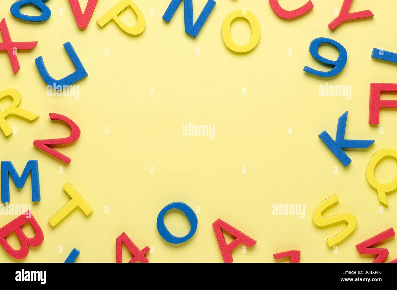 Lettere e numeri in schiuma colorata su sfondo giallo con spazio di copia. Foto Stock