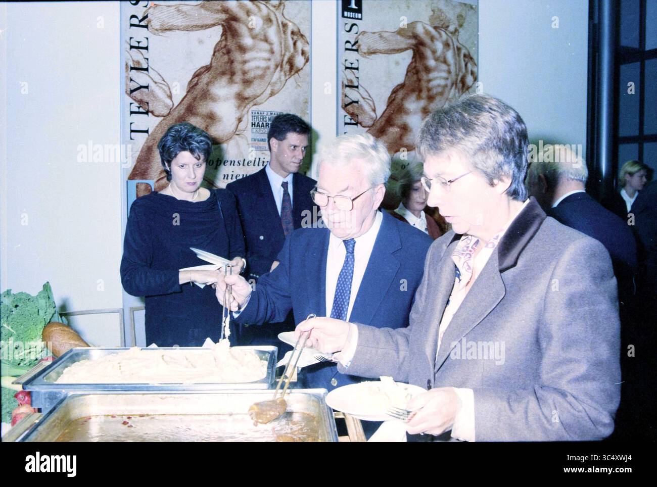 Anniversario N. Verloop, KPMG, Haarlem, Paesi Bassi, 14-11-1996 Whizgle News, Dutch Desk, Paesi Bassi, 1950-2000 Un gruppo di persone è riunito a un buffet, impegnato in una conversazione mentre serve cibo da un grande vassoio Gli individui vestiti elegantemente tengono i piatti mentre scelgono i loro pasti. Sullo sfondo, l'arte decorativa delle pareti aggiunge un tocco di atmosfera all'evento. Foto Stock