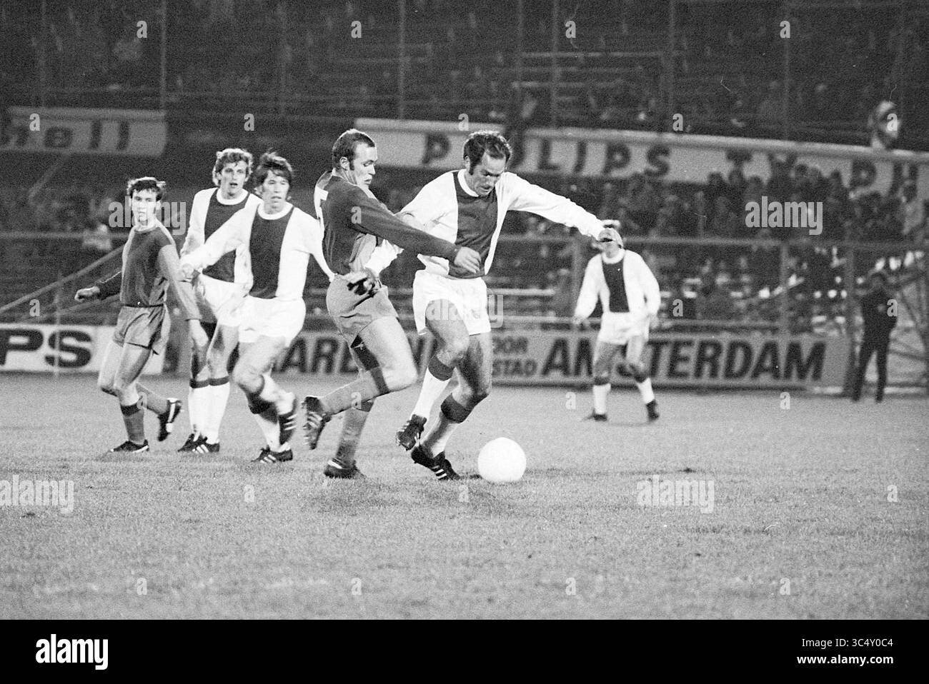 AJAX - F.C. Basel, Football Ajax, 21-10-1970 Whizgle News, Dutch Desk, Paesi Bassi, 1950-2000 Una scena dinamica di una classica partita di calcio, che mette in mostra i giocatori in azione intensa mentre competono per la palla sul campo. L'atmosfera è carica, con gli spettatori visibili in sottofondo, che aumentano l'emozione del gioco. Foto Stock