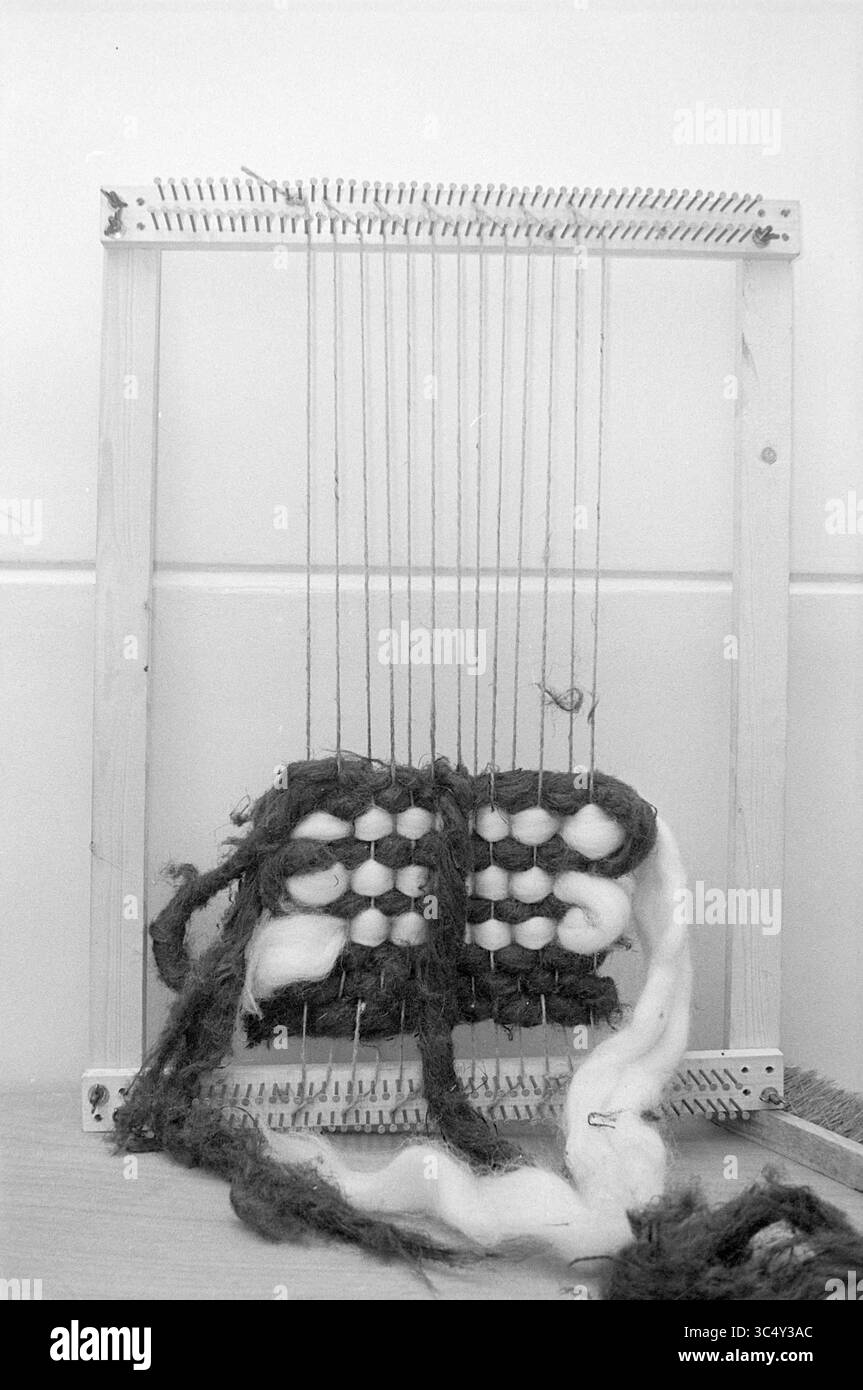 Jansen Weaving, Persons, 01-10-1973 Whizgle News, Dutch Desk, Paesi Bassi, 1950-2000 Un telaio in tessuto con fili e fibre varie, con un motivo parzialmente tessuto. La cornice contiene un mix di colori e texture, suggerendo un progetto creativo di tessitura in corso. Foto Stock
