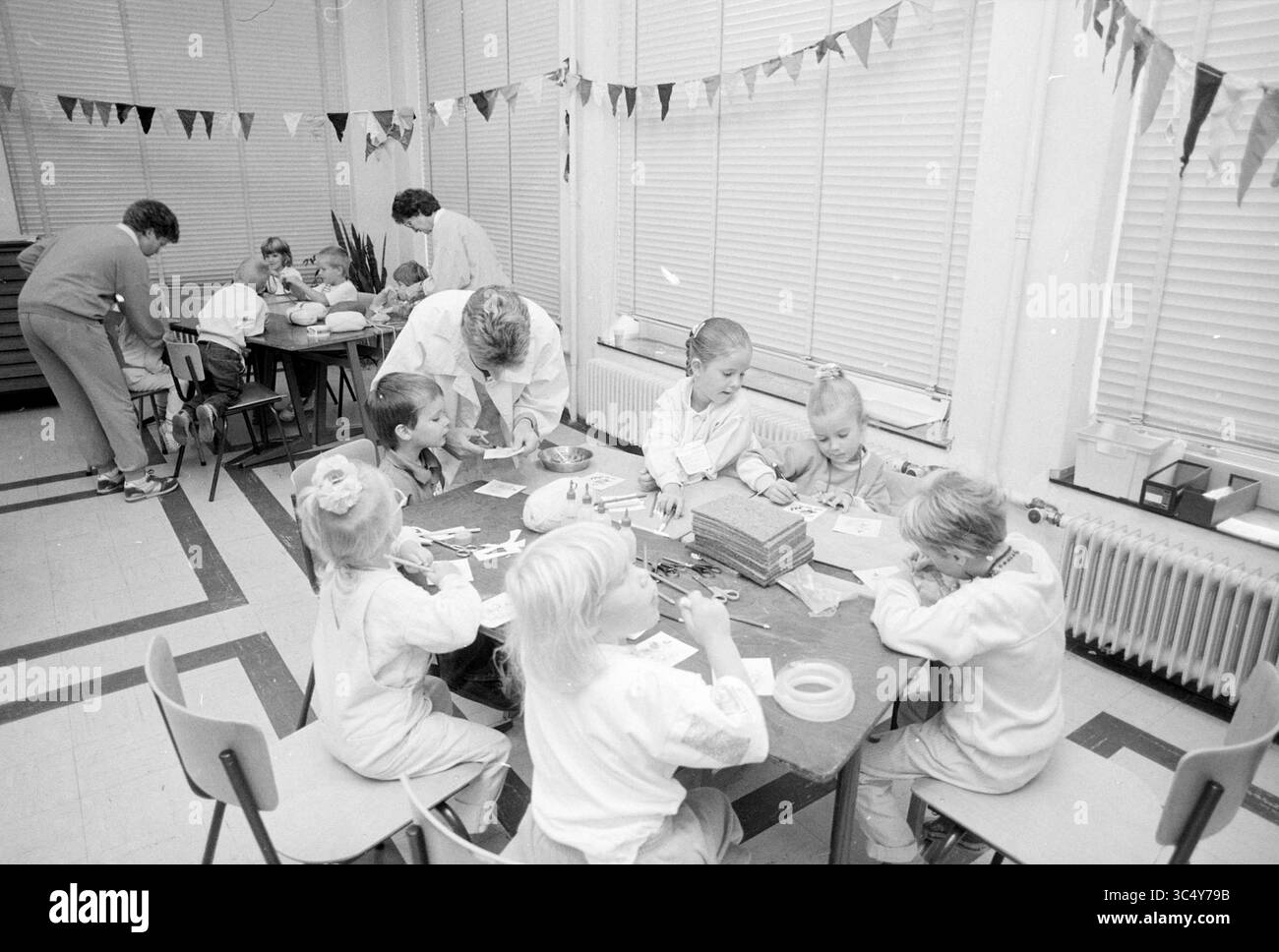 Giornata di gioco per il consiglio culturale dei bambini Hillegom, Giochi e giocattoli, Hillegom, 02-08-1989 Whizgle News, Dutch Desk, i Paesi Bassi, 1950-2000 Una vivace scena scolastica in cui bambini di varie età sono impegnati in attività creative ai tavoli, circondati da forniture artigianali. Alcuni adulti assistono i bambini, mentre un cane li osserva nelle vicinanze. Colorate cuciture adornano le pareti, esaltando l'atmosfera allegra. Foto Stock