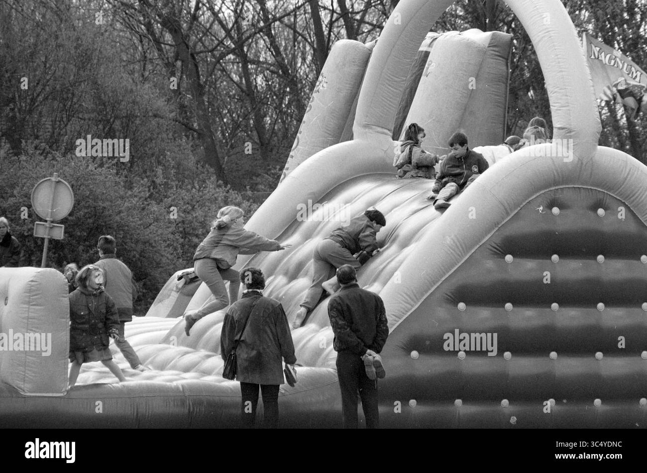Open Day Spaarnwoude, Velsen, Velsen, 19-04-1997 Whizgle News, Dutch Desk, i Paesi Bassi, 1950-2000 bambini si arrampicano e scivolano con gioia su una grande struttura gonfiabile, mentre gli adulti li guardano nelle vicinanze, creando una scena vivace piena di risate e giochi. Gli alberi sullo sfondo aggiungono un tocco naturale all'atmosfera festosa. Foto Stock