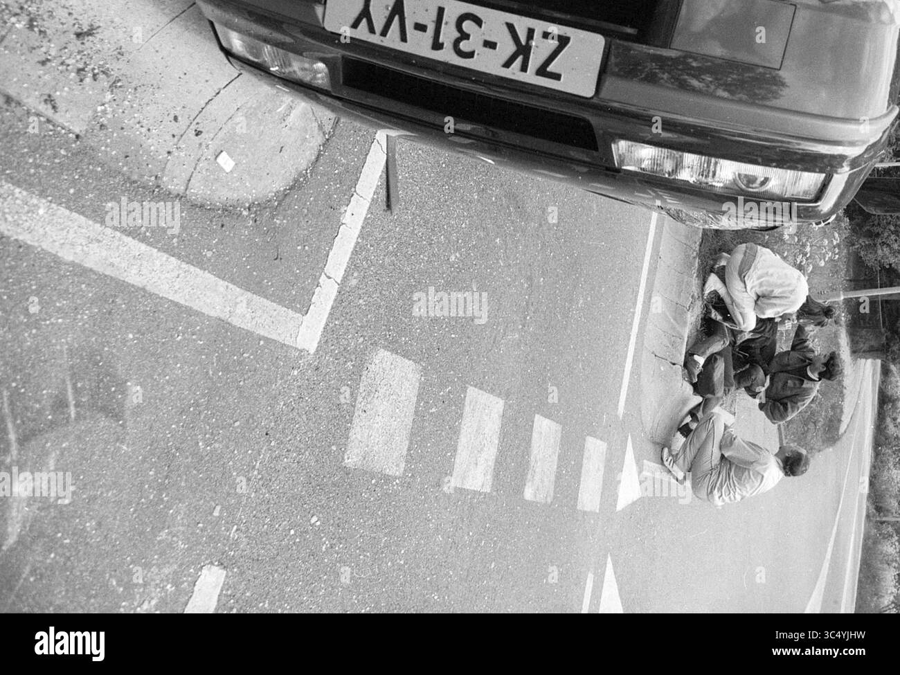 Accident Military Road, 21-05-1991 Whizgle News, Dutch Desk, Paesi Bassi, 1950-2000 due individui sono visti impegnati in un'attività sul ciglio della strada vicino a un veicolo parcheggiato in un angolo. I dintorni includono segnaletica stradale e vegetazione, suggerendo una scena ambientata in un'area urbana o suburbana. Foto Stock