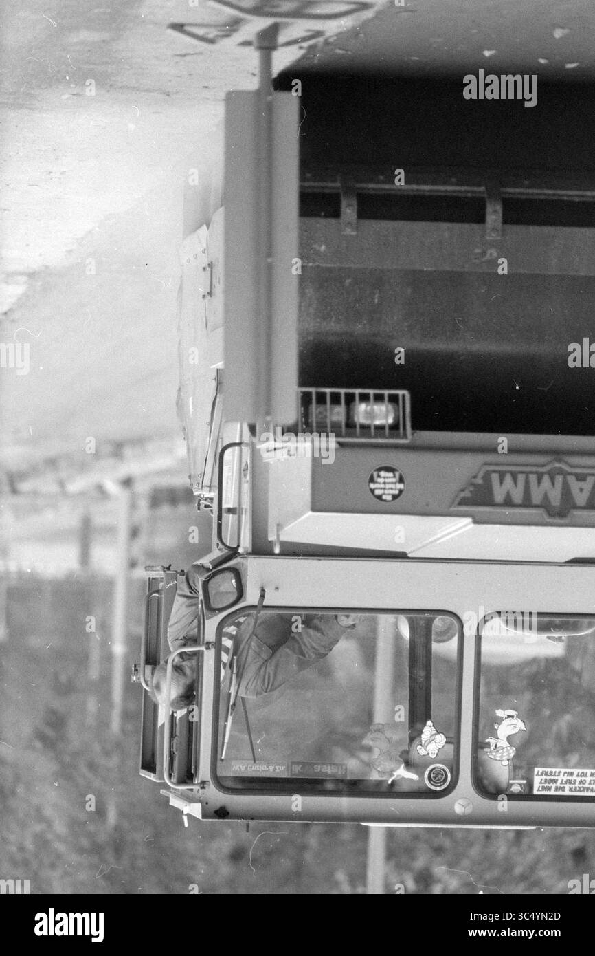 Asfaltando Velserend, 31-10-1991 Whizgle News, Dutch Desk, Paesi Bassi, 1950-2000 Un autobus viene catturato da una prospettiva insolita, con una persona visibile sul sedile del conducente, circondata da vari adesivi e un profilo laterale unico del veicolo. La scena trasmette un senso di movimento e di vita urbana. Foto Stock