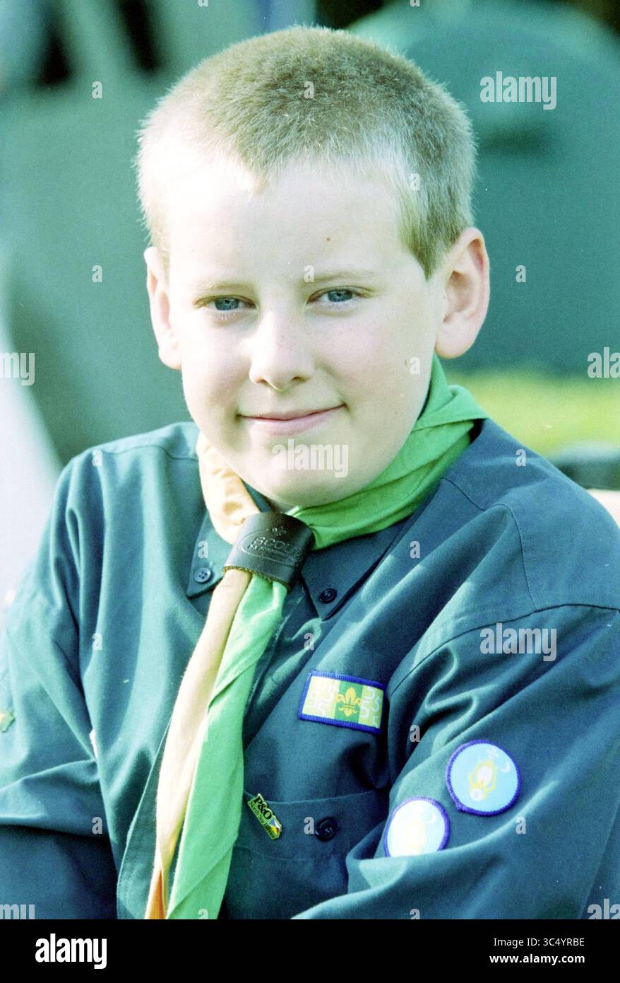 Jamborette, Spaarnwoude, Spaarnwoude, 26-07-2003 Whizgle News, Dutch Desk, i Paesi Bassi, 1950-2000 Anni Un giovane scout sorride con fiducia, indossando un'uniforme verde scuro decorata con distintivi e un capo collana, che mostra un senso di orgoglio e cameratismo nella comunità degli scout. Foto Stock