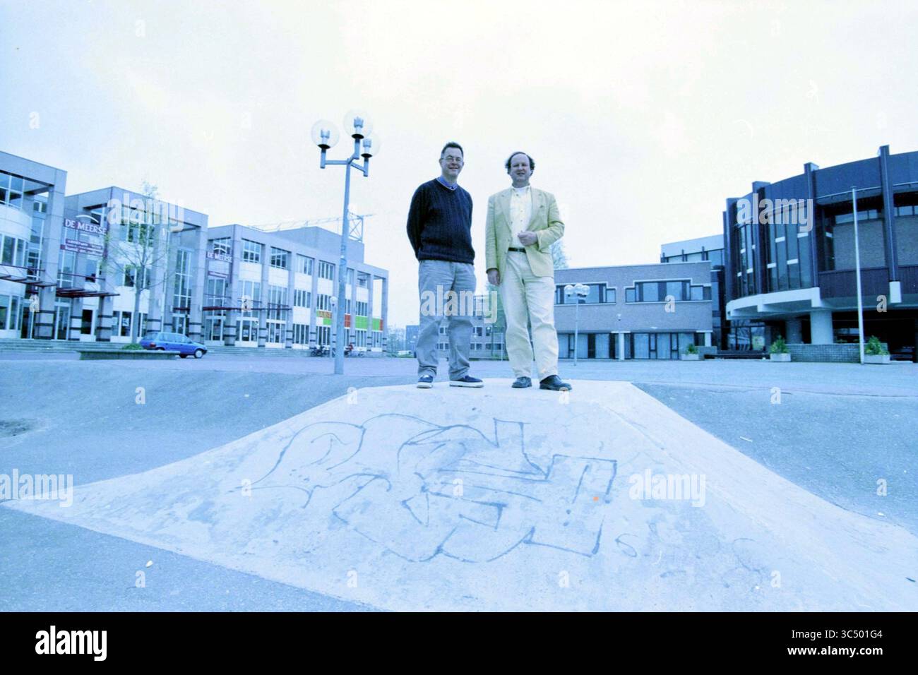 Organization More Jazz, 08-04-2002 Whizgle News, Dutch Desk, Paesi Bassi, 1950-2000 due persone si trovano fianco a fianco su una piccola rampa in un ambiente urbano, con edifici moderni sullo sfondo. La scena presenta alcuni alberi e lampioni stradali, e il terreno presenta alcuni graffiti artistici. Foto Stock