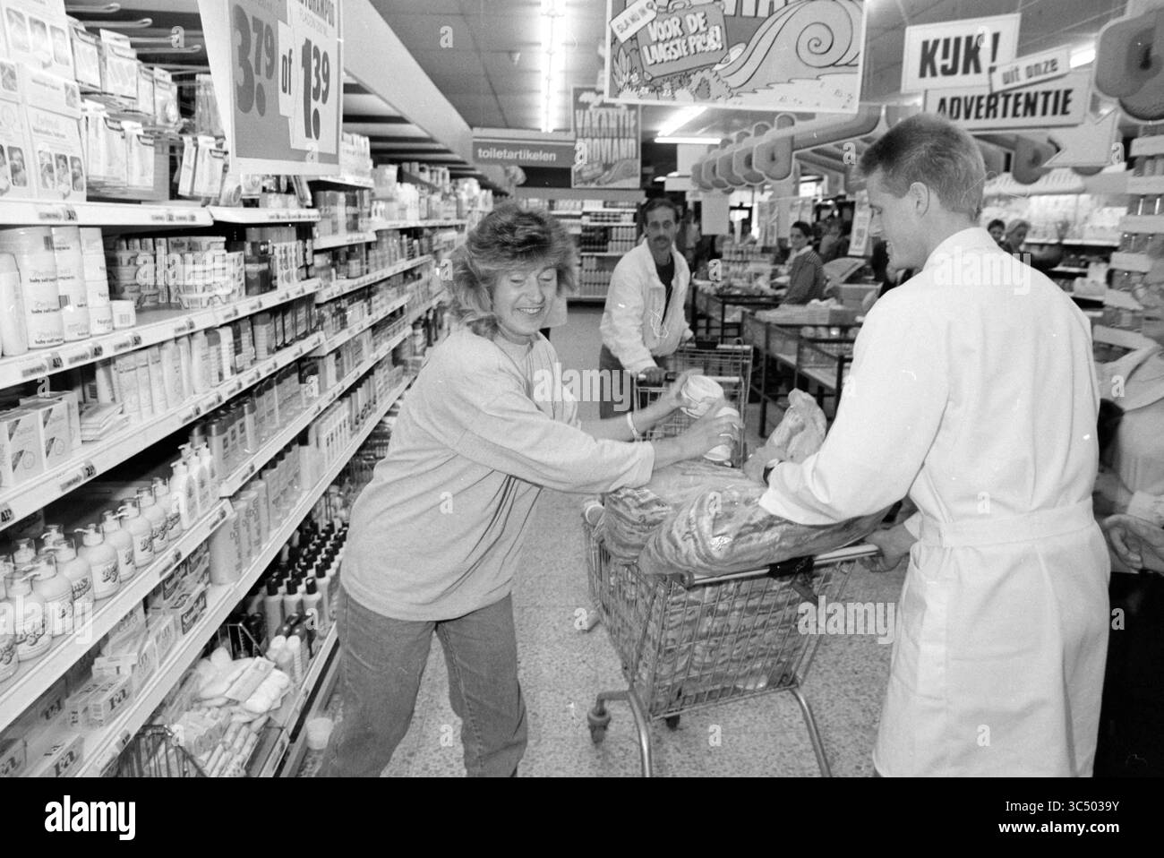 Due minuti di shopping gratuito a Zandvoort, Zandvoort, 09-06-1990 Whizgle News, Dutch Desk, Paesi Bassi, 1950-2000 Una vivace scena di supermercati cattura gli acquirenti impegnati nella loro routine, con una donna che spinge con gioia un carrello pieno di generi alimentari, mentre altre due navigano nelle corsie, mostrando un'atmosfera vivace della vita quotidiana. Foto Stock