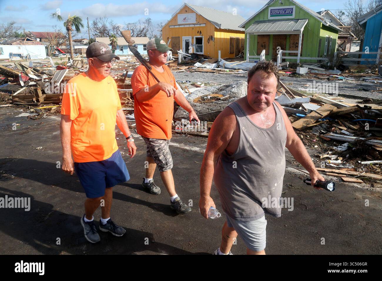11 ottobre 2018 - Mexico Beach, Florida, Stati Uniti - da sinistra: AL CATHEY, 71, LEE CATHEY, 37 e CHARLES SMITH, 56, rilevamento danni nella township costiera di Mexico Beach, popolazione di 1200 abitanti, devastati giovedì dopo l'uragano Michael sbarcato mercoledì nella Florida Panhandle. Al, che ha detto di essere il sindaco, crede che 280 residenti abbiano cavalcato la tempesta nelle loro case. Lee aveva trovato il suo fucile nel mezzo di US 98, che fu spostato dal suo negozio di ferramenta durante la tempesta. (Immagine di credito: © Douglas R. Clifford/Tampa Bay Times via cavo ZUMA) Foto Stock