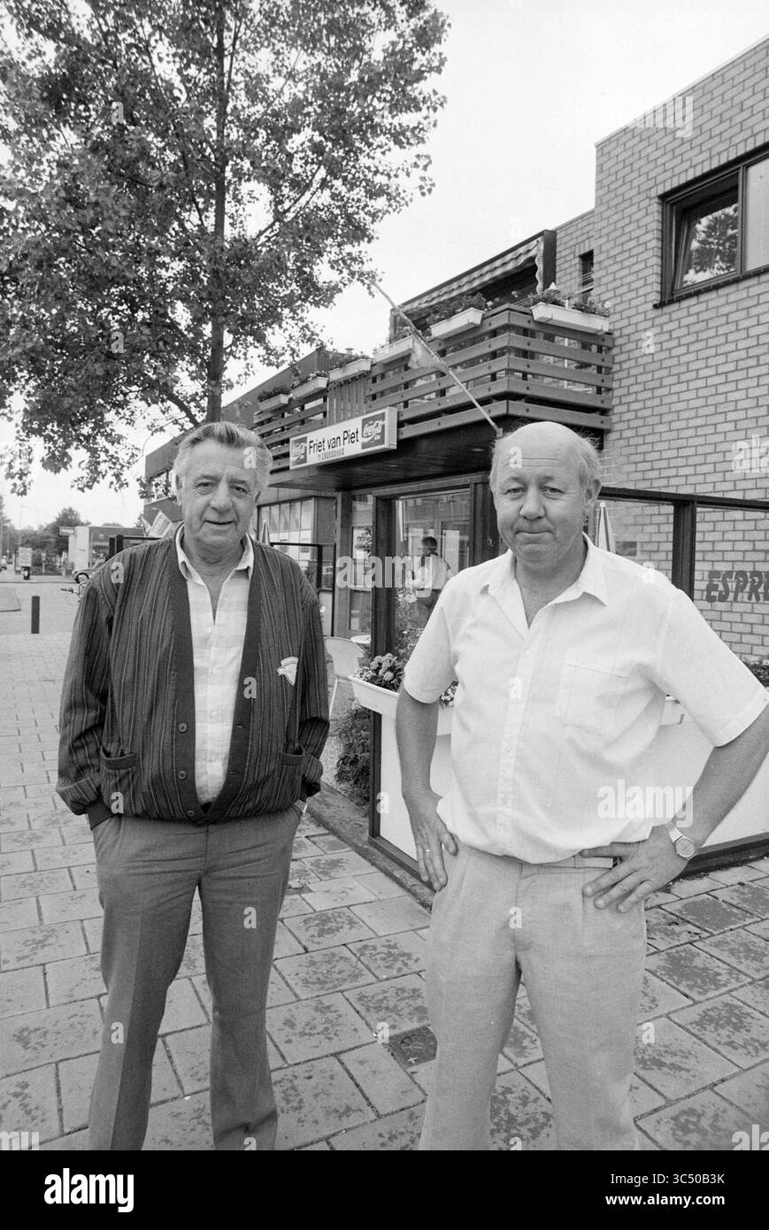 Snack bar Fries from Piet, Haarlem, Belgiëlaan, Paesi Bassi, 00-06-1988 Whizgle News, Dutch Desk, Paesi Bassi, 1950-2000 due uomini si alzano con sicurezza davanti a un negozio, vestiti casualmente con camicie button-up. Lo sfondo presenta un albero e un edificio moderno con un cartello che sembra pubblicizzare un'azienda. Le loro espressioni suggeriscono familiarità, poichè si mettono insieme in modo amichevole. Foto Stock