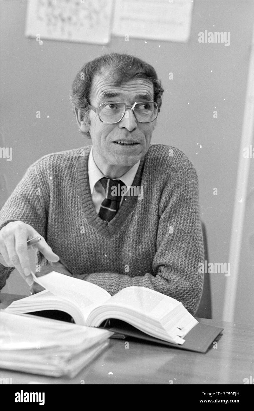 OPPURE Haarlem, VNU Association of Dutch Publishers, Haarlem, Paesi Bassi, 23-02-1983 Whizgle News, Dutch Desk, i Paesi Bassi, 1950-2000 Un uomo in maglia e cravatta è impegnato in una discussione, gestendo mentre è seduto a un tavolo con un libro aperto davanti a lui. Documenti e documenti sono sparsi sul tavolo, indicando un ambiente accademico. Foto Stock OPPURE Haarlem, VNU Association of Dutch Publishers, Haarlem, Paesi Bassi, 23-02-1983 Whizgle News, Dutch Desk, i Paesi Bassi, 1950-2000 Un uomo in maglia e cravatta è impegnato in una discussione, gestendo mentre è seduto a un tavolo con un libro aperto davanti a lui. Documenti e documenti sono sparsi sul tavolo, indicando un ambiente accademico. Foto Stock