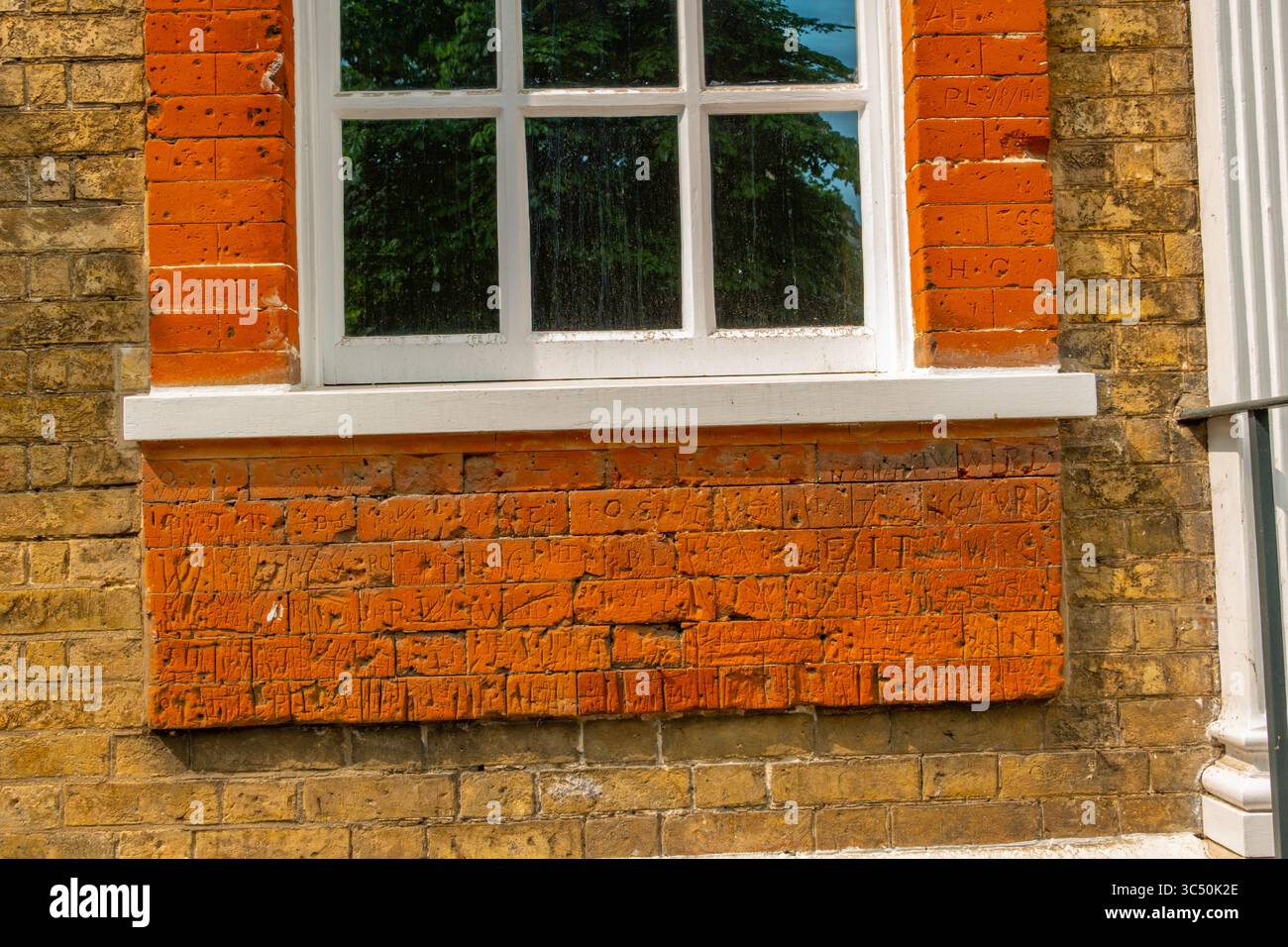 Vecchi graffiti tagliati nei mattoni di Shermans, High St Dedham Essex Foto Stock