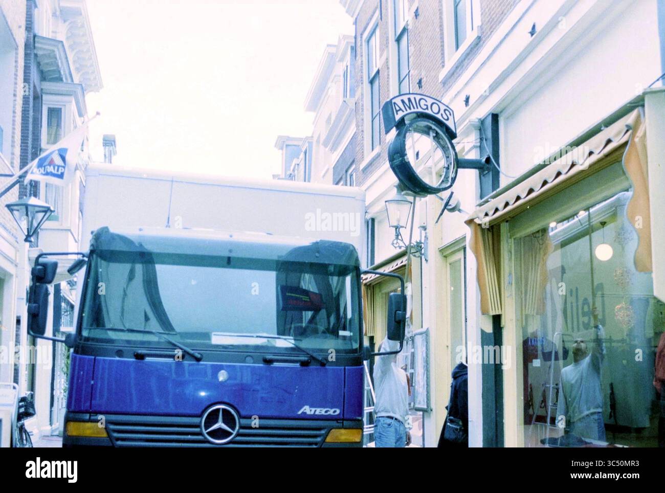 Il camion si schianta contro l'orologio di Haarlem, Haarlem, Paesi Bassi, 03-12-2001 Whizgle News, Dutch Desk, paesi Bassi, 1950-2000 Un camion blu è parcheggiato in una strada stretta, con un cartello con la scritta "AMIGOS" appeso sopra un negozio. L'architettura circostante presenta edifici in stile tradizionale, e nelle vicinanze si possono vedere persone impegnate in varie attività. Foto Stock