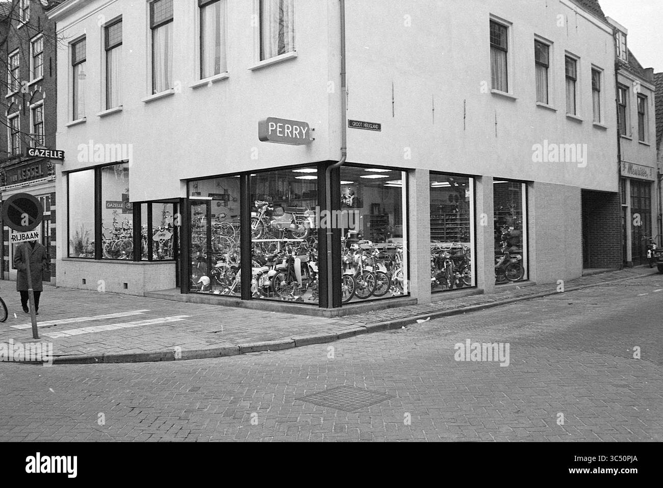 Fa. Perry, esterno, 12-02-1970 Whizgle News, Dutch Desk, Paesi Bassi, 1950-2000 Un vivace negozio d'angolo con grandi finestre espone una varietà di biciclette, per soddisfare i clienti sulla strada trafficata. La segnaletica dell'edificio mostra in modo prominente "PERRY", mentre i passanti navigano sul marciapiede nelle vicinanze. Foto Stock